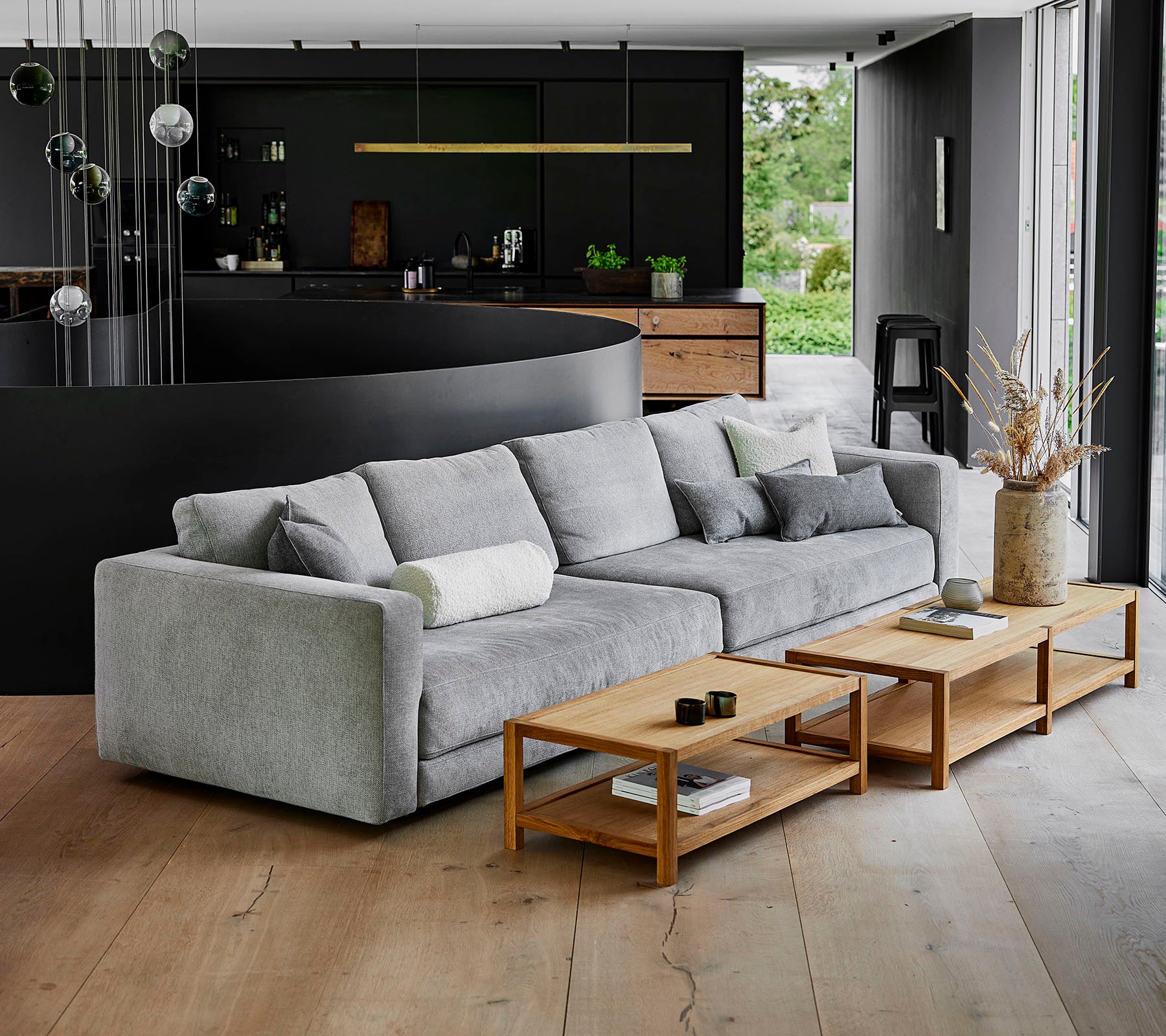 Un canapé moderne gris avec des coussins moelleux à côté de tables basses en bois dans un cadre contemporain avec une décoration élégante.