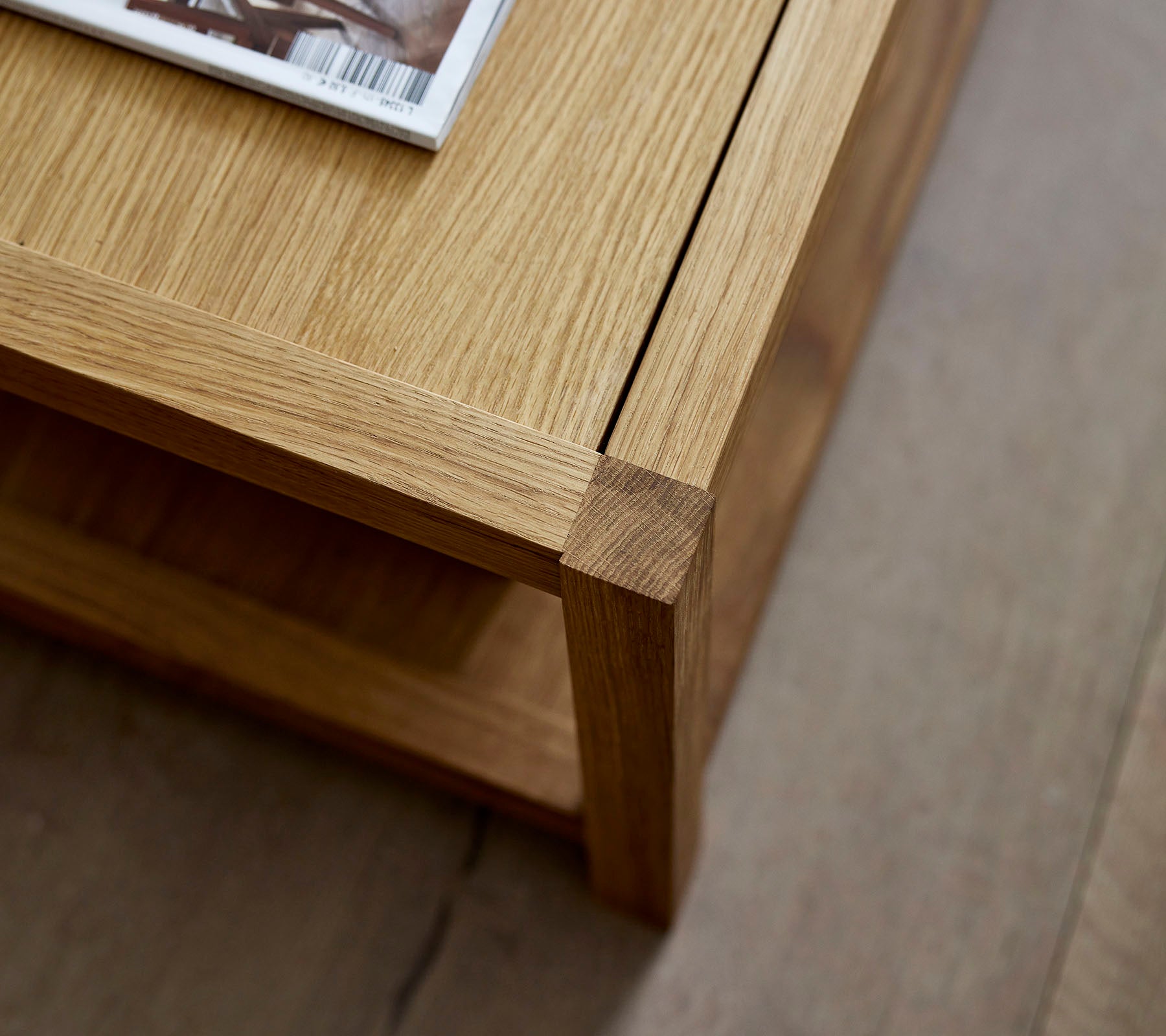 Table basse en bois au design épuré, avec un magazine placé dessus et une étagère inférieure minimaliste pour un rangement supplémentaire.