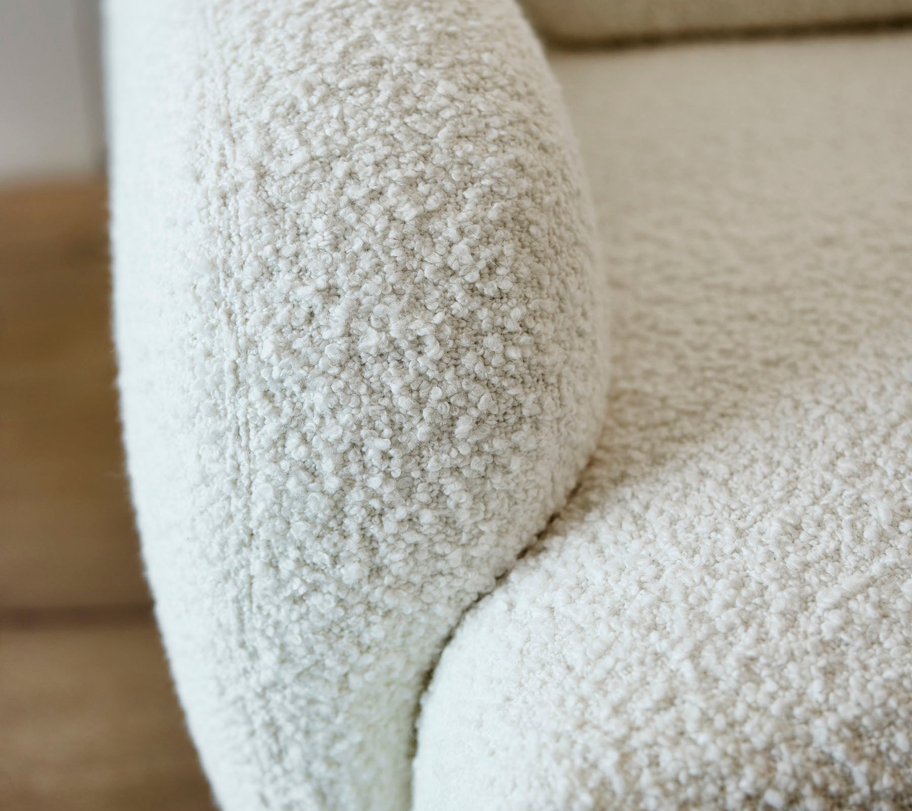 Gros plan d'un accoudoir de canapé blanc texturé avec une surface douce et duveteuse, ajoutant une esthétique chaleureuse et accueillante à tout espace.