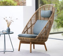 Chaise tissée élégante avec un dossier haut, un siège rembourré et un coussin assorti, accompagnée d'une petite table et d'un vase décoratif.