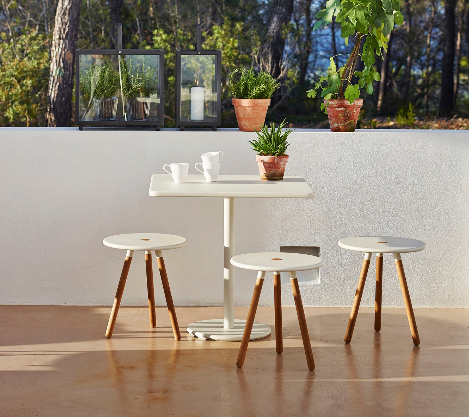 Une table minimaliste avec trois tabourets assortis, entourée de plantes en pot, créant une atmosphère sereine et invitante.