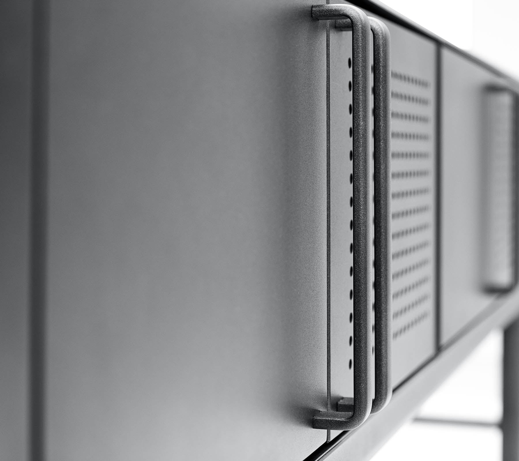 Gros plan sur une surface métallique moderne et épurée avec une poignée et des détails de ventilation, mettant en valeur un design minimaliste.