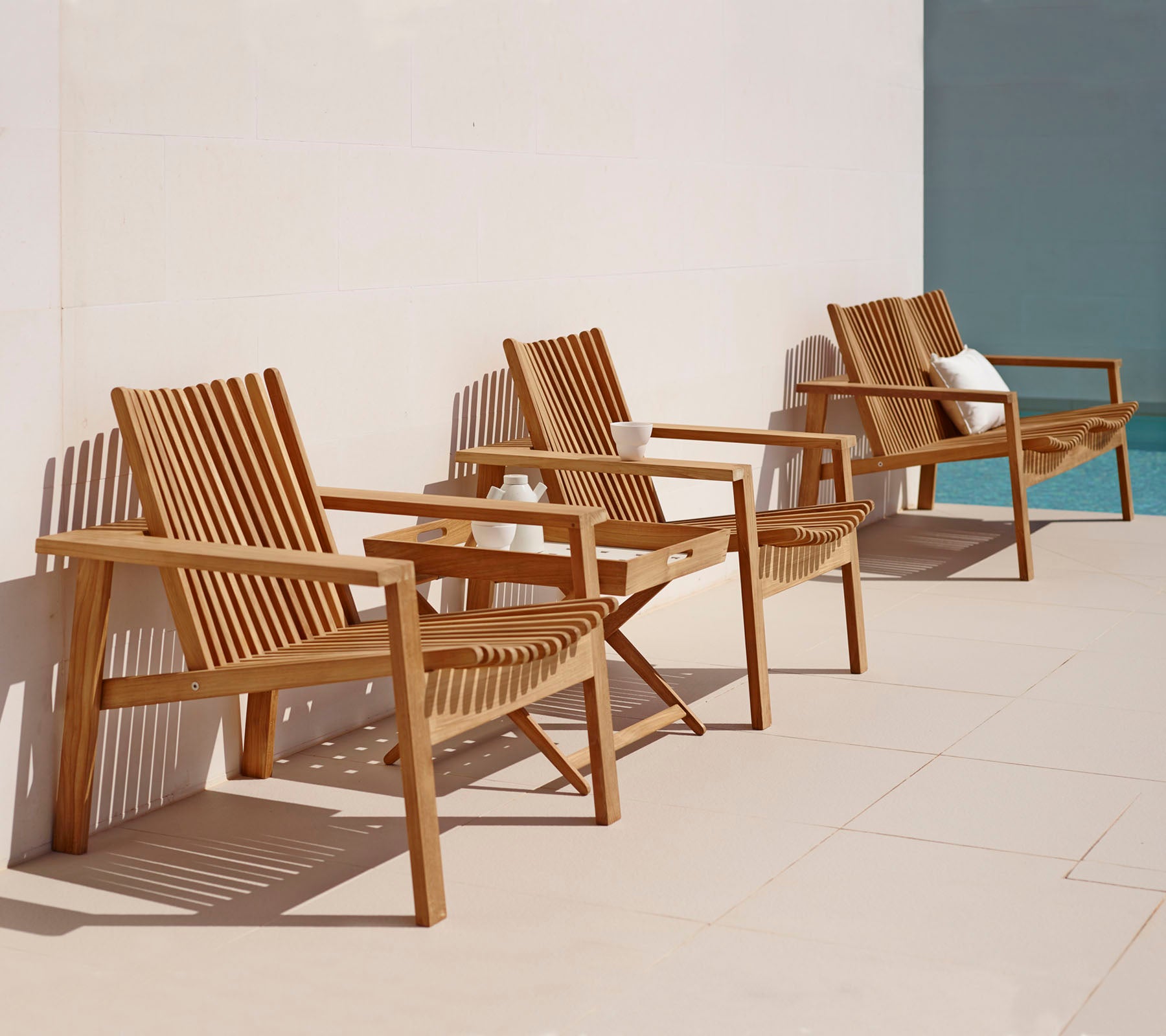 Trois chaises longues en bois avec un design en lattes disposées en rangée, présentant un style simple et élégant adapté à la détente.