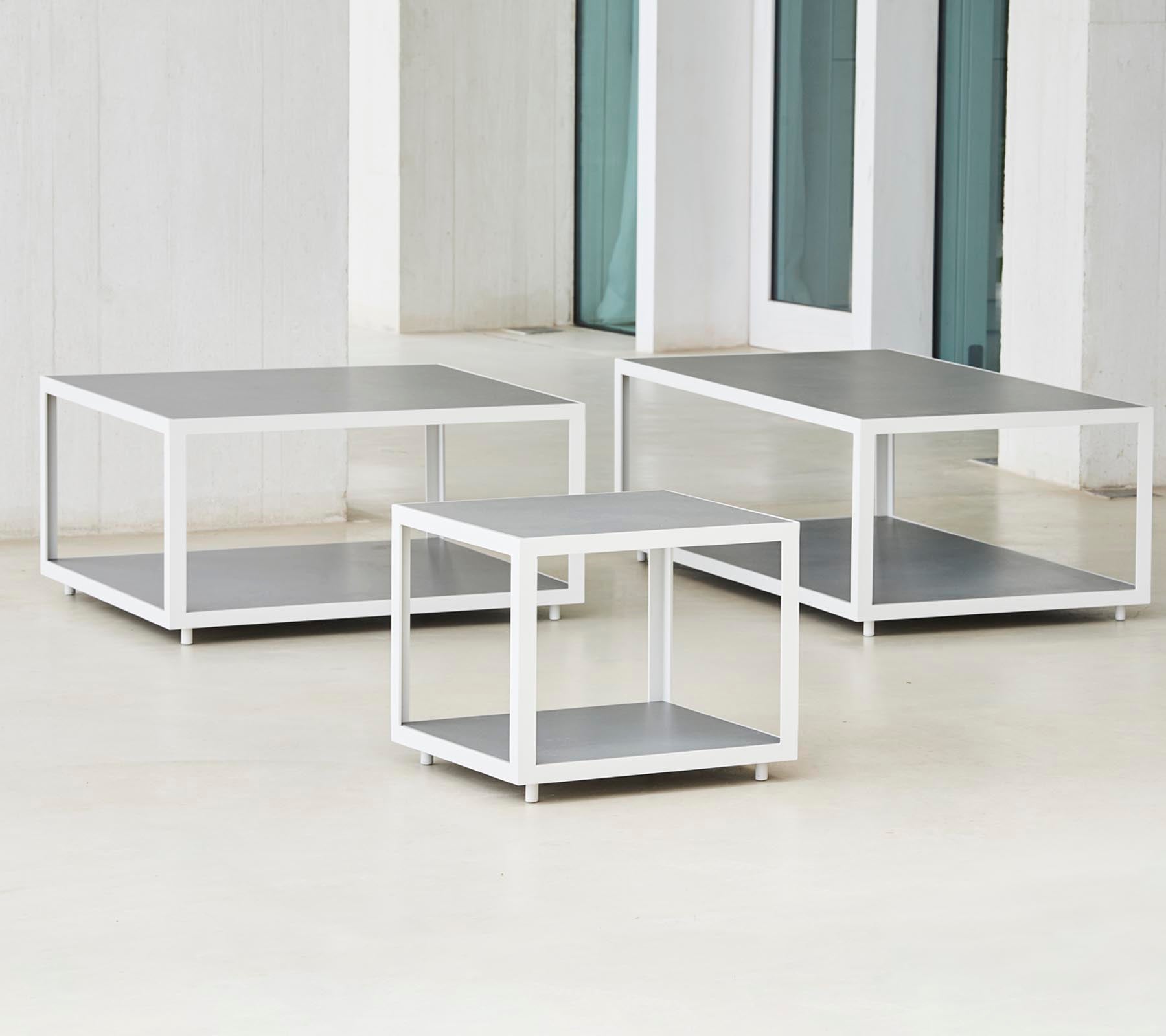 Un ensemble de trois tables modernes au design élégant avec des cadres en métal et des surfaces planes, disposées en différentes tailles.