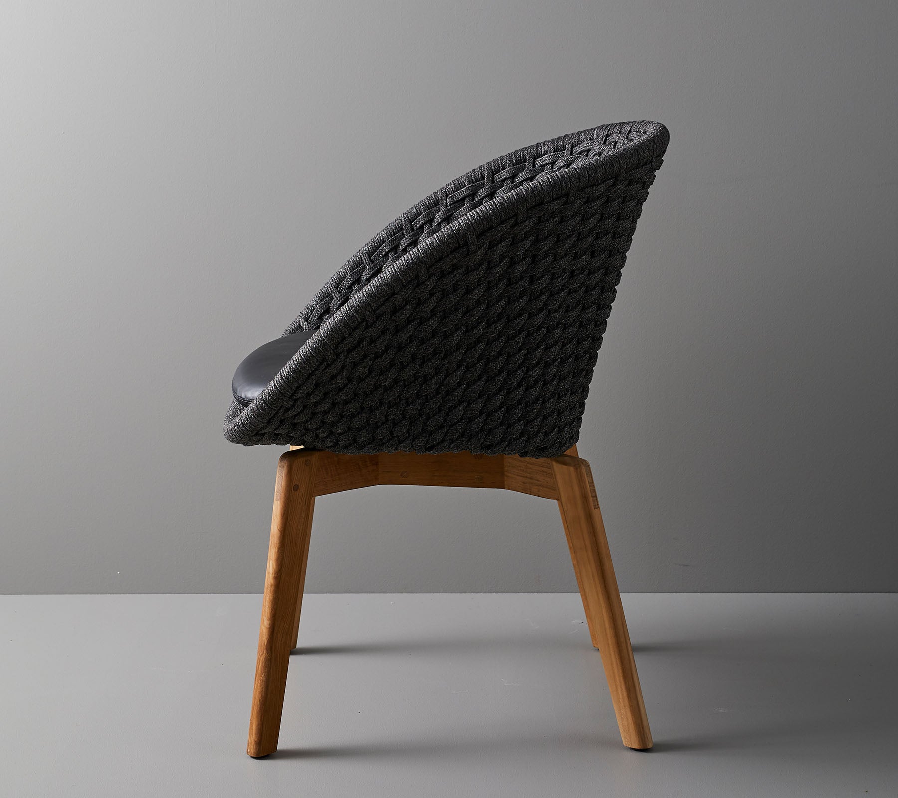 Chaise élégante avec un dossier tissé et des pieds en bois, offrant un design moderne idéal pour des espaces contemporains.