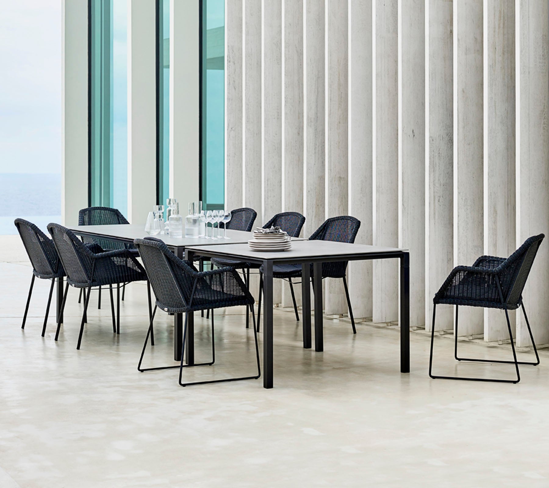 Un ensemble de salle à manger moderne avec des chaises noires disposées autour, présentant des éléments de design minimalistes et une mise en place de table élégante.