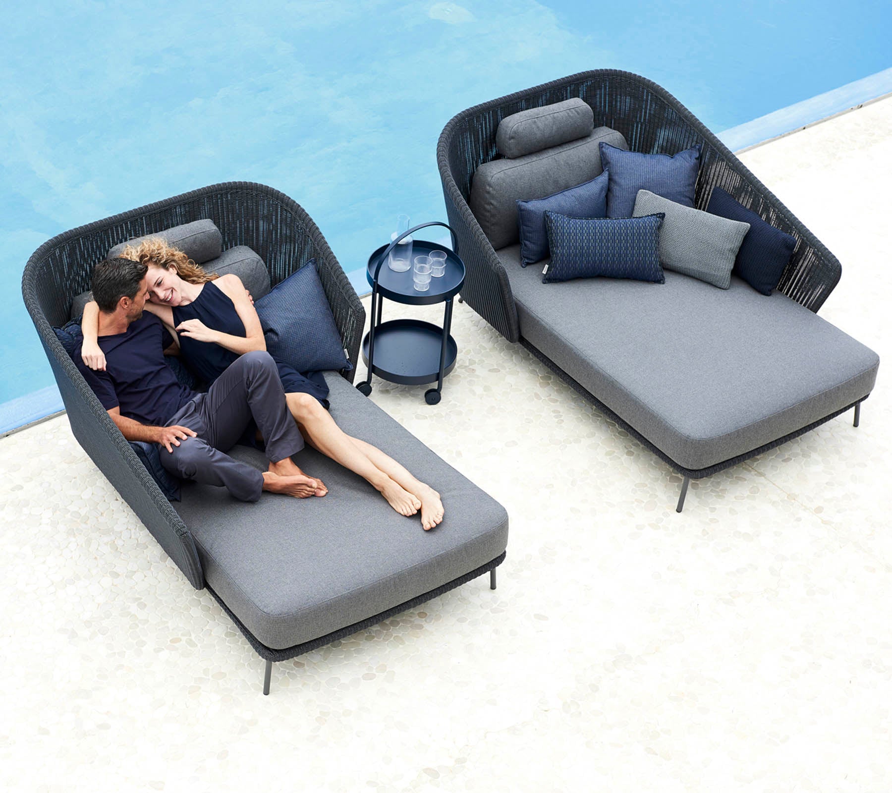 Un couple se détend ensemble sur des fauteuils lounge élégants avec des coussins moelleux, accompagné d'une petite table d'appoint et de coussins décoratifs.