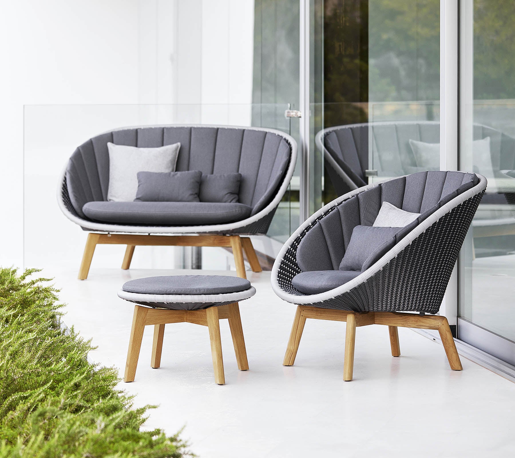 Ensemble de sièges élégant comprenant un canapé courbé, une chaise et une table basse ronde, le tout avec un design moderne et des coussins gris doux.