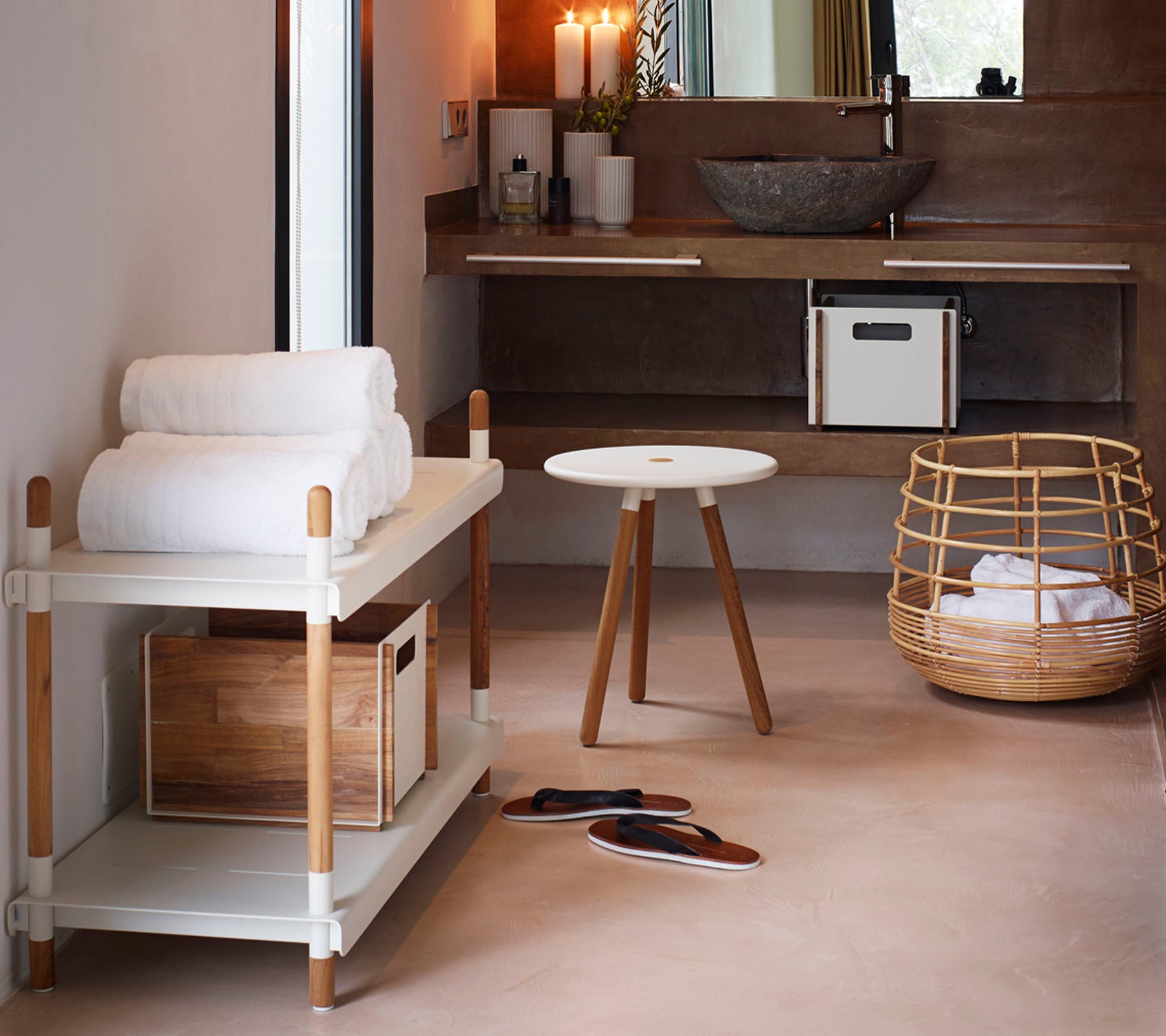 Un espace minimaliste avec un porte-serviettes contenant des serviettes pliées, une petite table ronde et un panier en osier, créant une atmosphère chaleureuse.