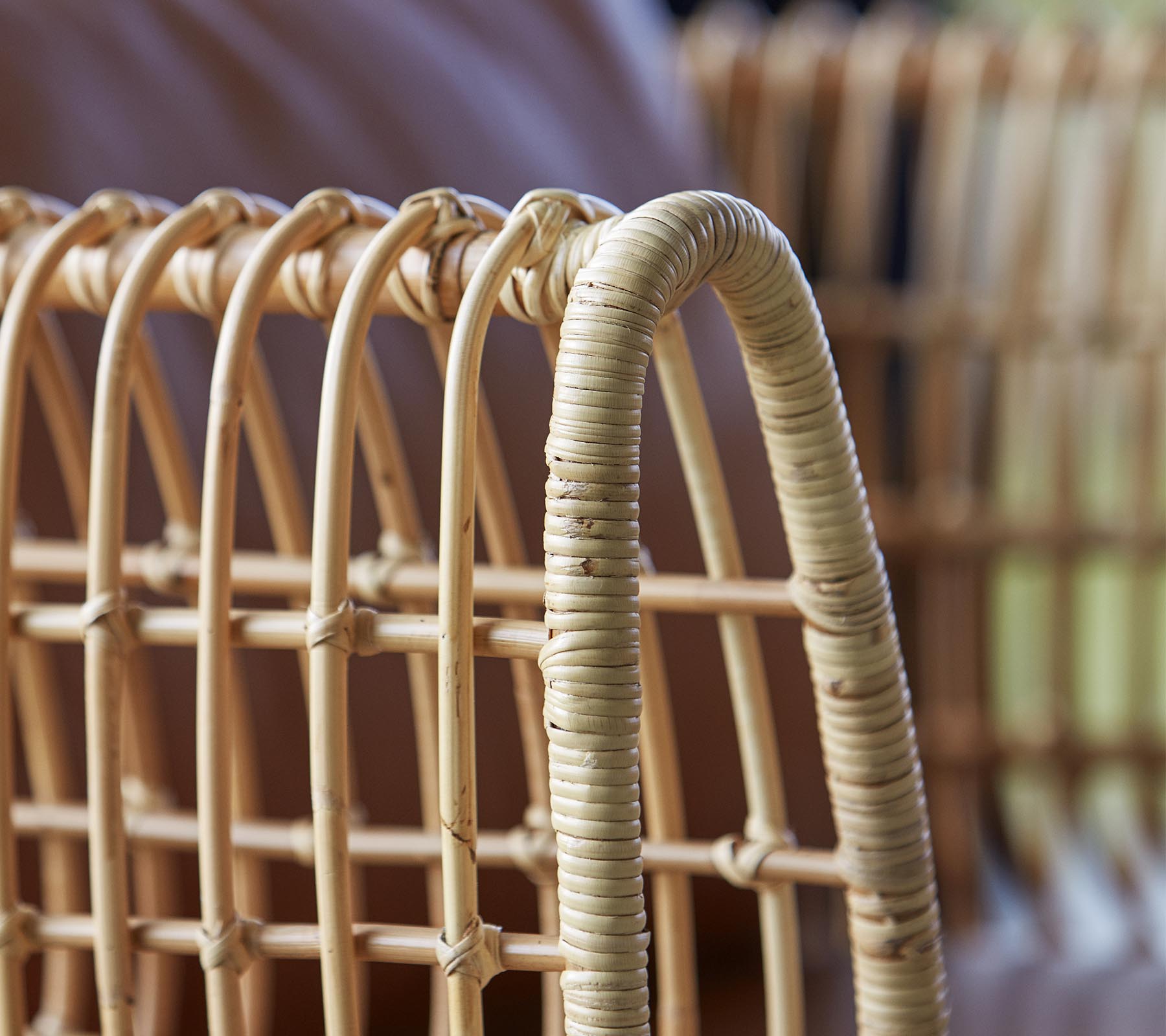 Gros plan d'une chaise en rotin tressé, présentant des lignes courbes et une finition naturelle, mettant en avant son artisanat et son design.