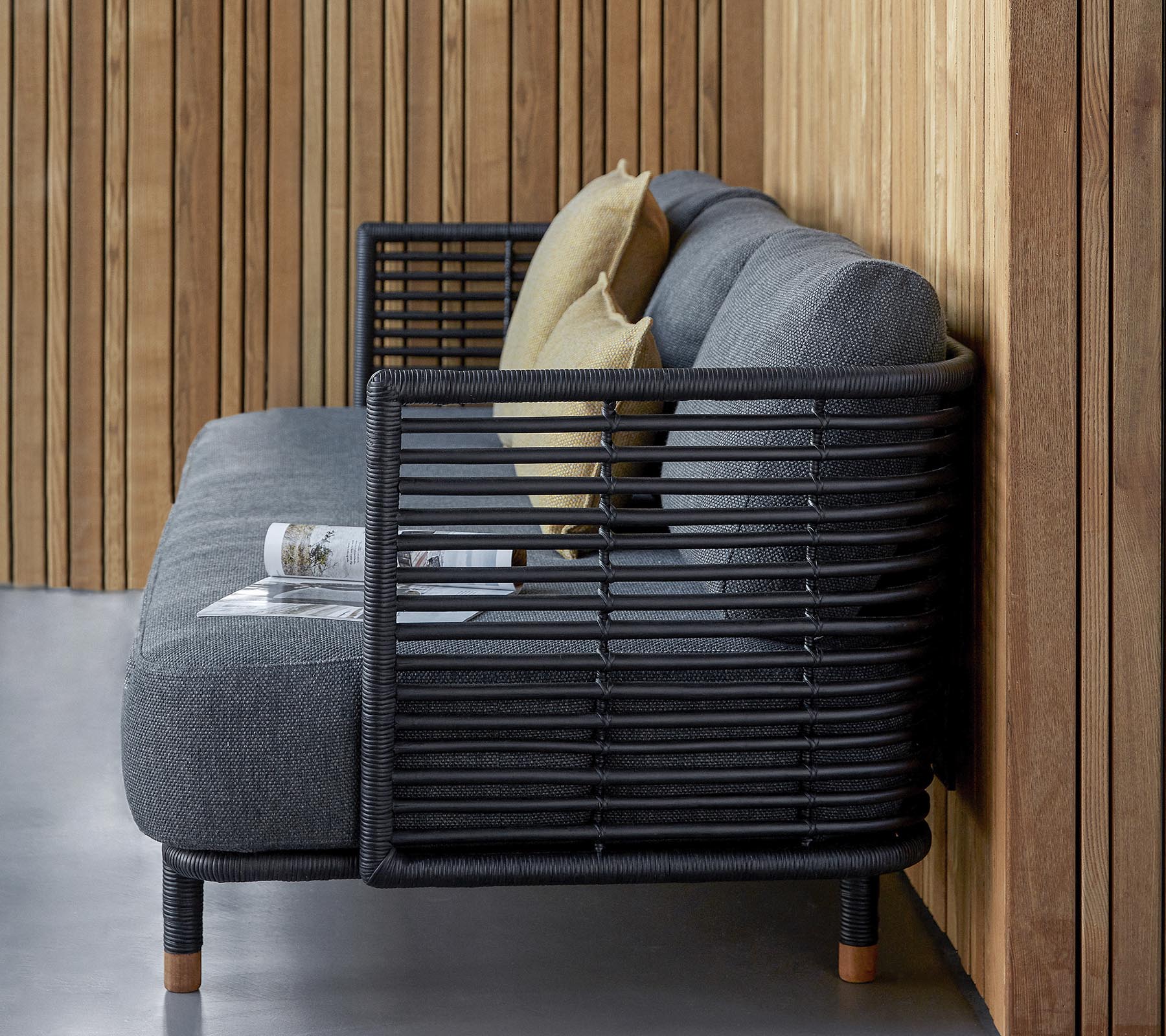 Canapé élégant avec un design épuré en tissu gris texturé et des coussins décoratifs, complété par un cadre à lattes moderne.