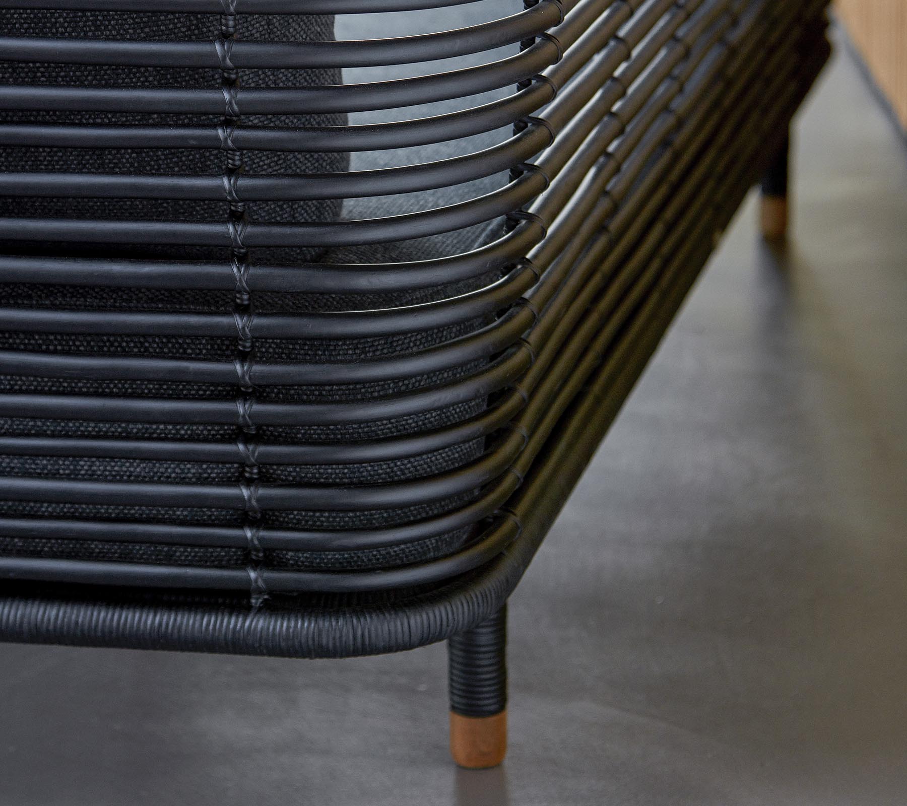 Mobilier tissé noir élégant avec des lignes courbes et des accents en bois, mettant en avant une esthétique de design moderne. Un ajout parfait à tout espace.