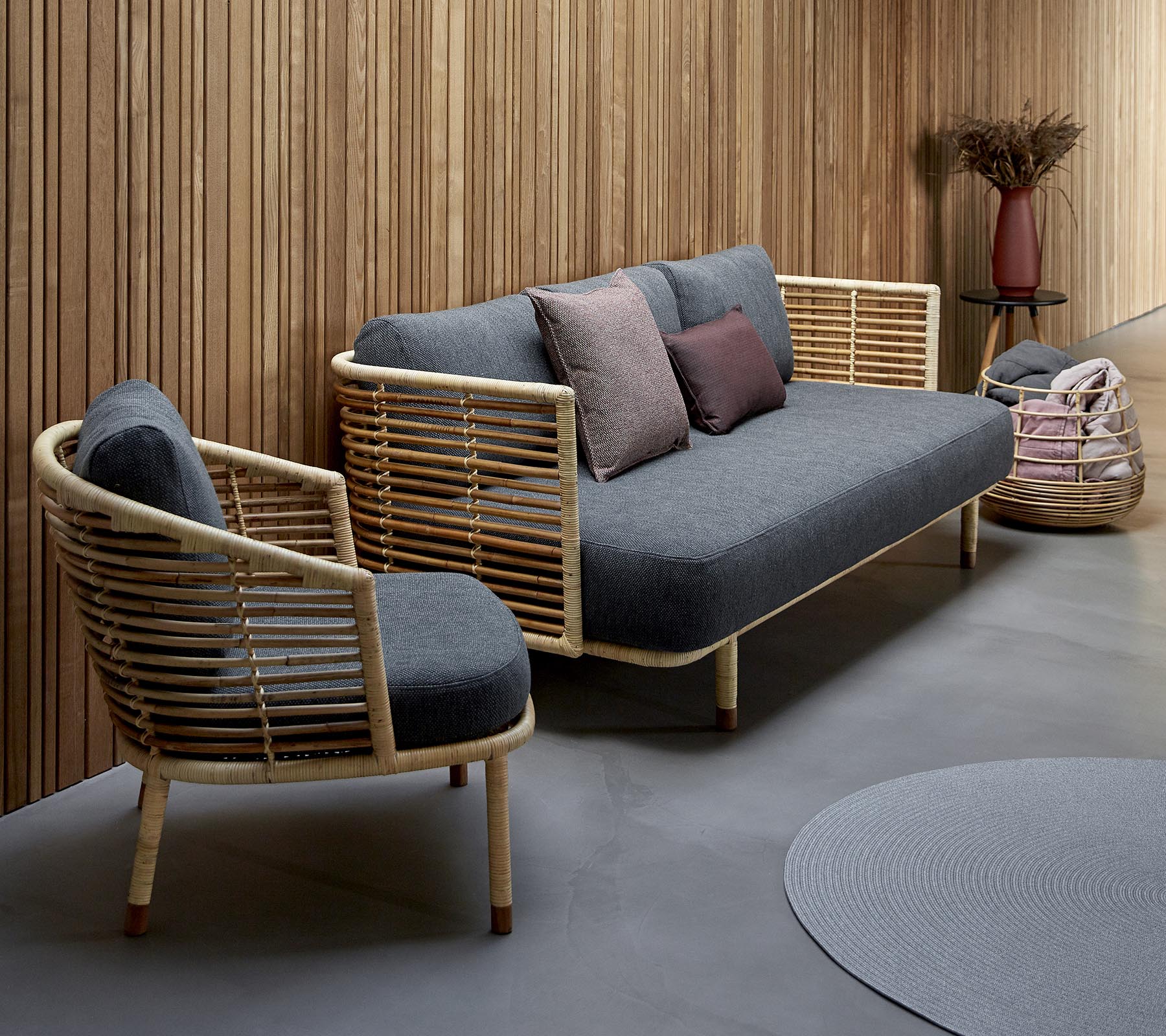 Agencement de sièges élégant avec un canapé gris tapissé de bois et une chaise assortie, complété par des coussins décoratifs.