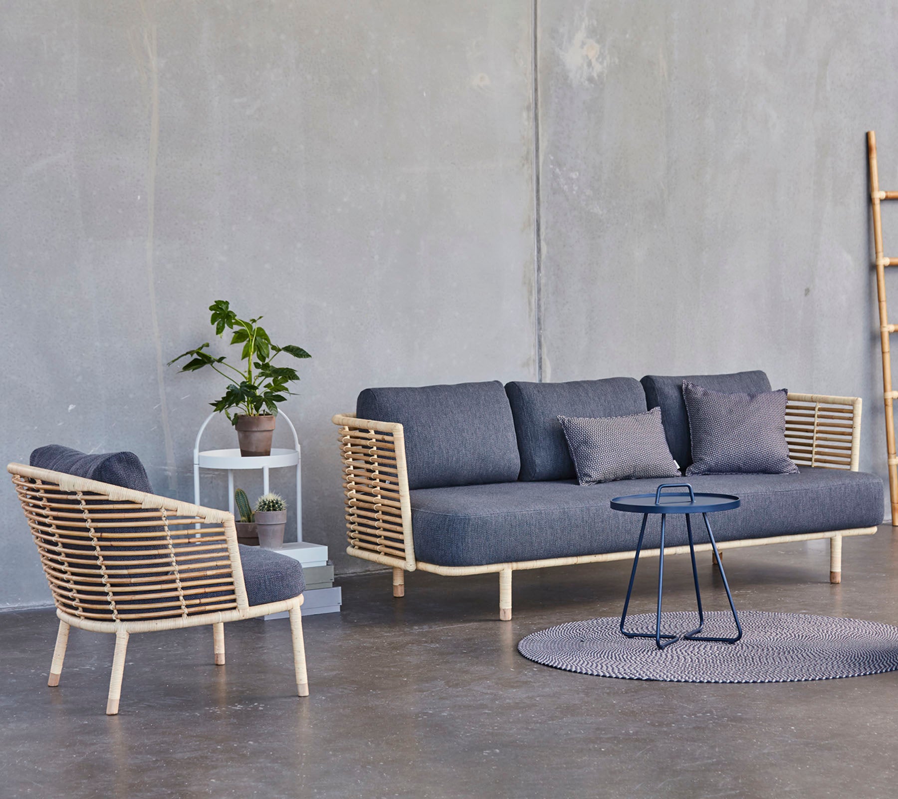 Un agencement moderne avec un canapé élégant et un fauteuil avec des accents en bois, accompagné d'une petite table d'appoint et d'une plante en pot.