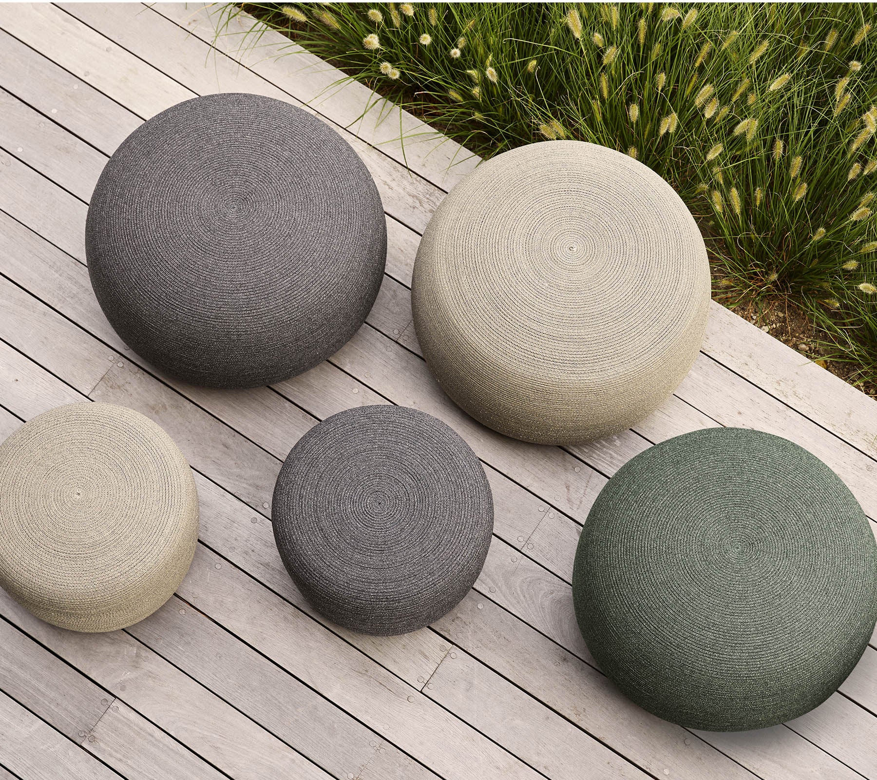 Un ensemble de cinq poufs ronds de différentes tailles et couleurs, avec des surfaces texturées qui apportent une touche moderne à tout espace.