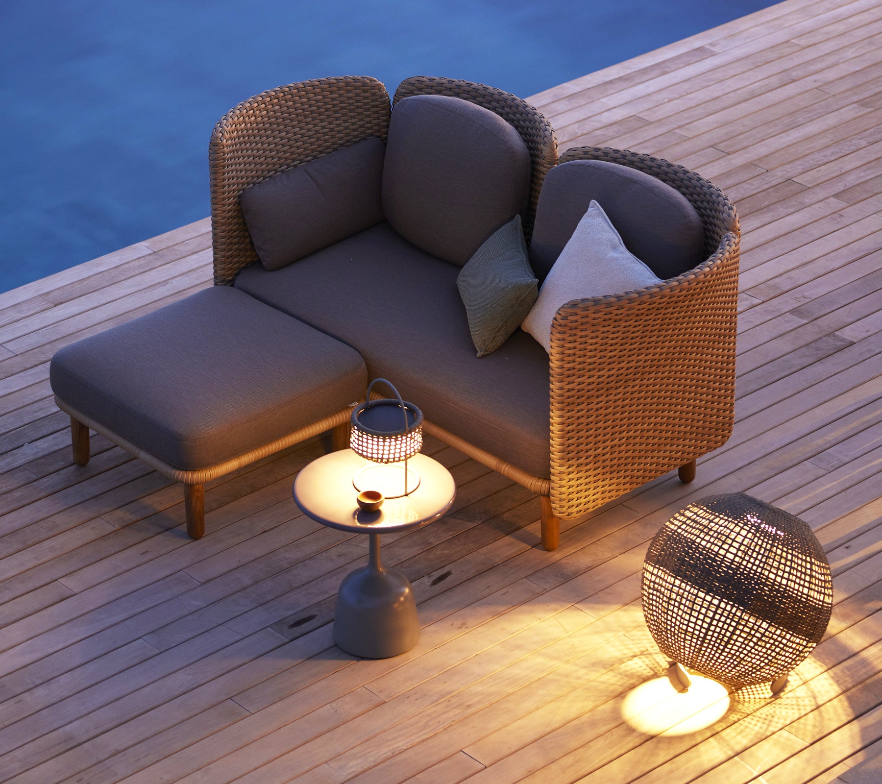 Canapé 2 places confortable avec un dossier bas, accompagné d'une petite table d'appoint et d'une lanterne décorative. Parfait pour se détendre.