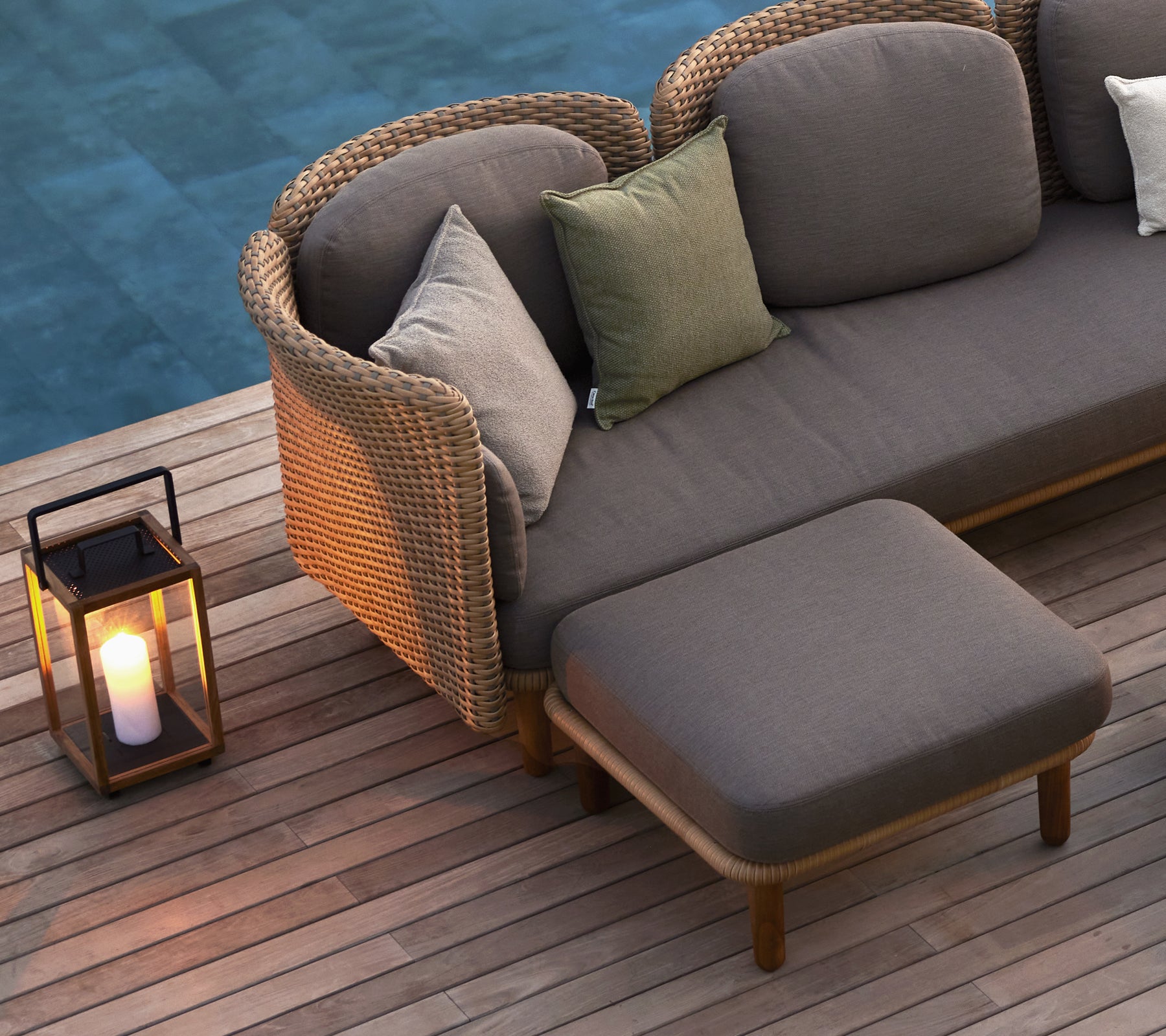 Un coin salon confortable avec un canapé et des coussins et une lanterne, qui améliore l'ambiance avec une lumière chaleureuse.