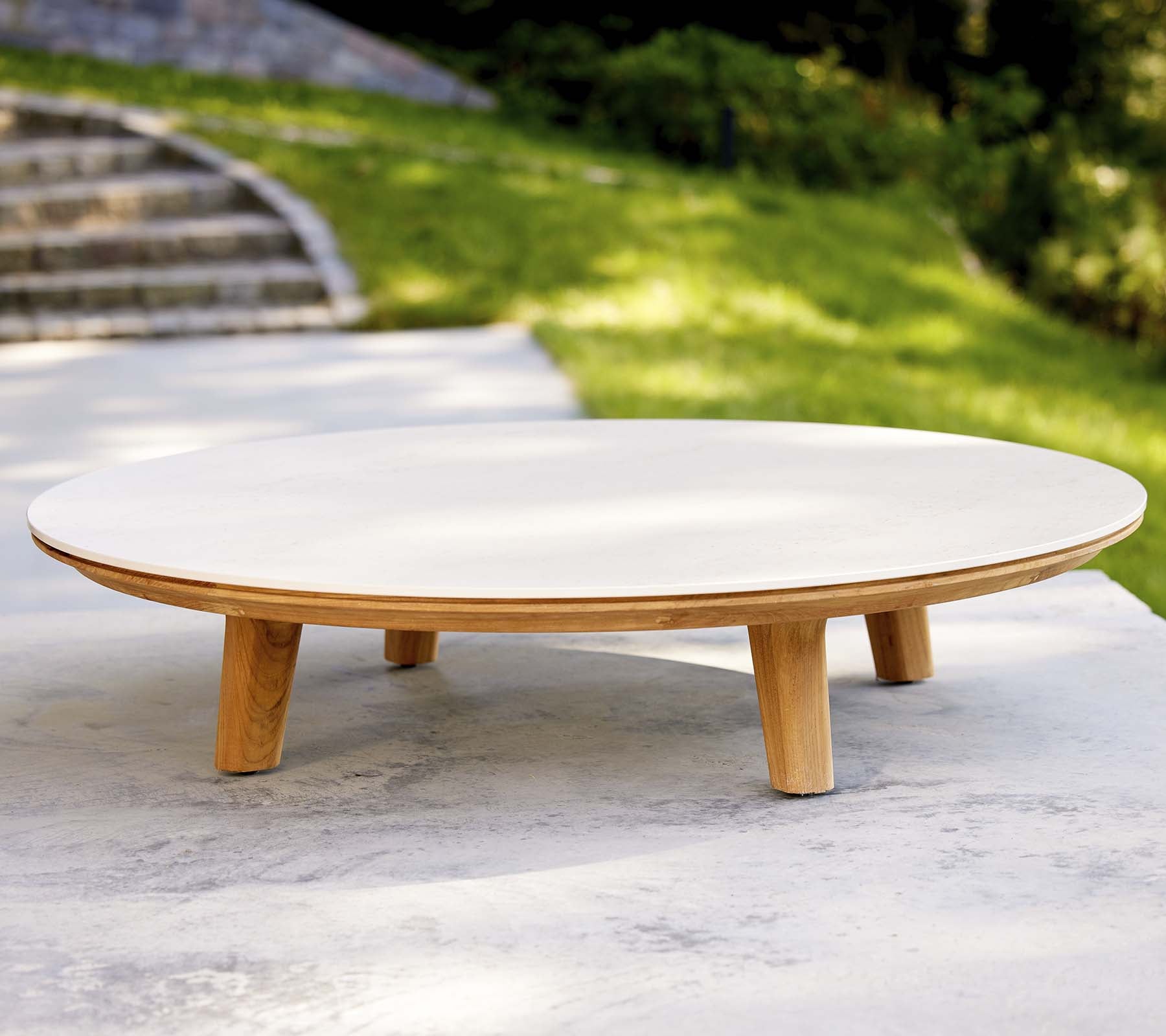 Table basse ronde moderne avec une surface lisse et des pieds en bois, présentant un design minimaliste adapté à divers environnements.