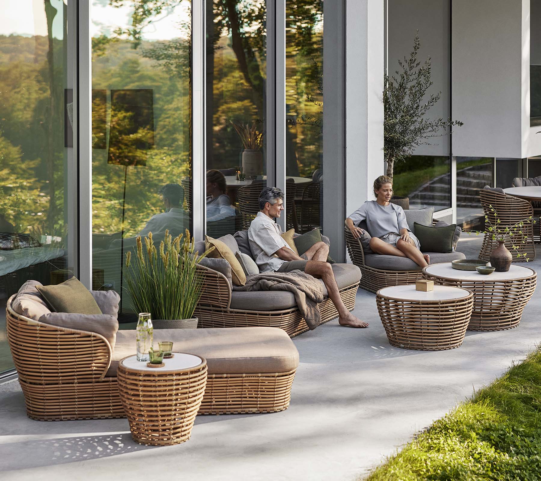Espace de seating élégant avec un lit de soleil en panier, un fauteuil et une table basse avec des éléments naturels, créant une atmosphère cosy et relaxante.