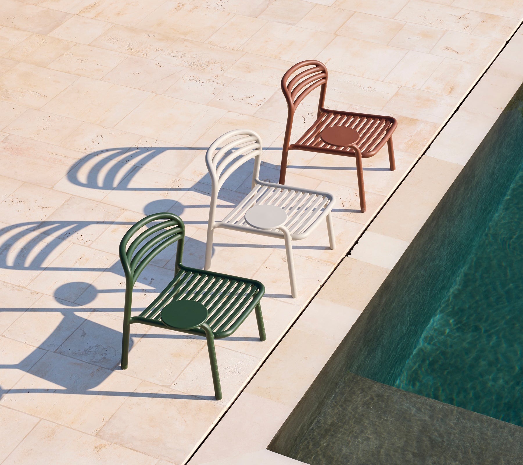 Trois chaises modernes en vert, blanc et marron à côté d'une piscine.
