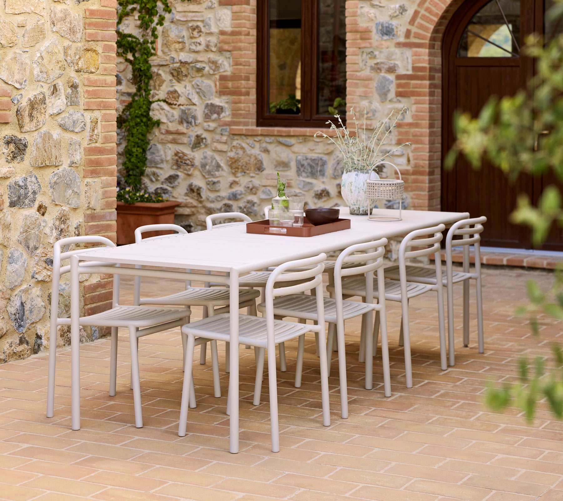 Un aménagement moderne de salle à manger avec une table Bliss, des chaises Bliss et un plateau Club sur une surface texturée.