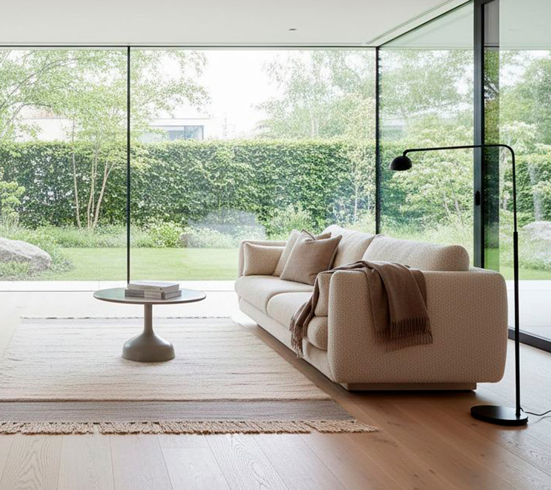 Canapé blanc moderne avec une lampe de sol noire et une table basse ronde dans un salon minimaliste.