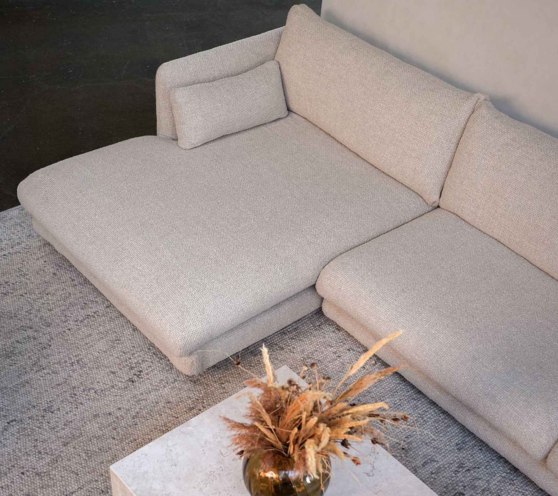 Canapé beige moderne avec une table blanche et un vase décoratif dans un cadre de salon élégant.