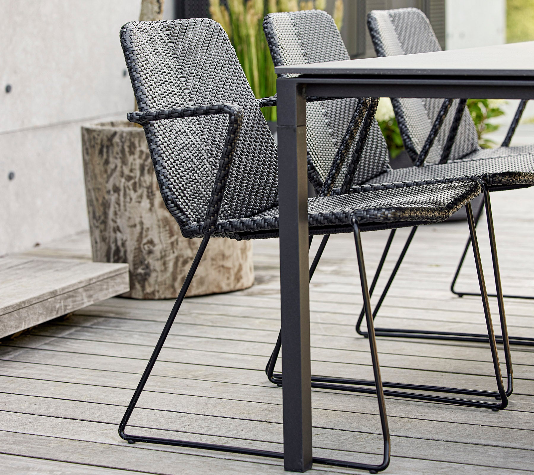 Un ensemble de chaises noires modernes tissées autour d'une table élégante, mettant en valeur le design contemporain et le savoir-faire.
