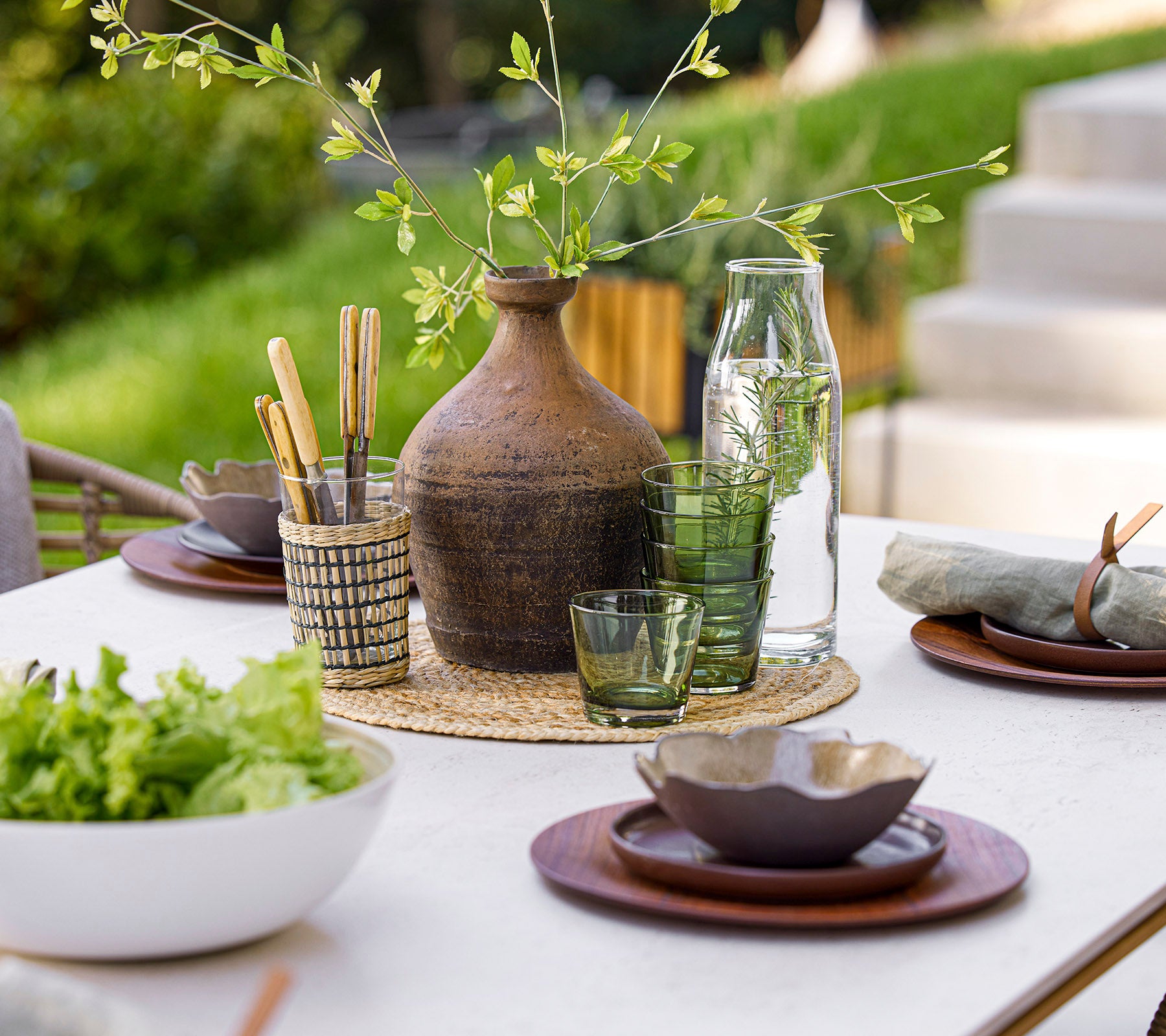 Une table à manger magnifiquement dressée avec de la verrerie, des éléments naturels et de la vaisselle élégante, créant une atmosphère de repas sereine.