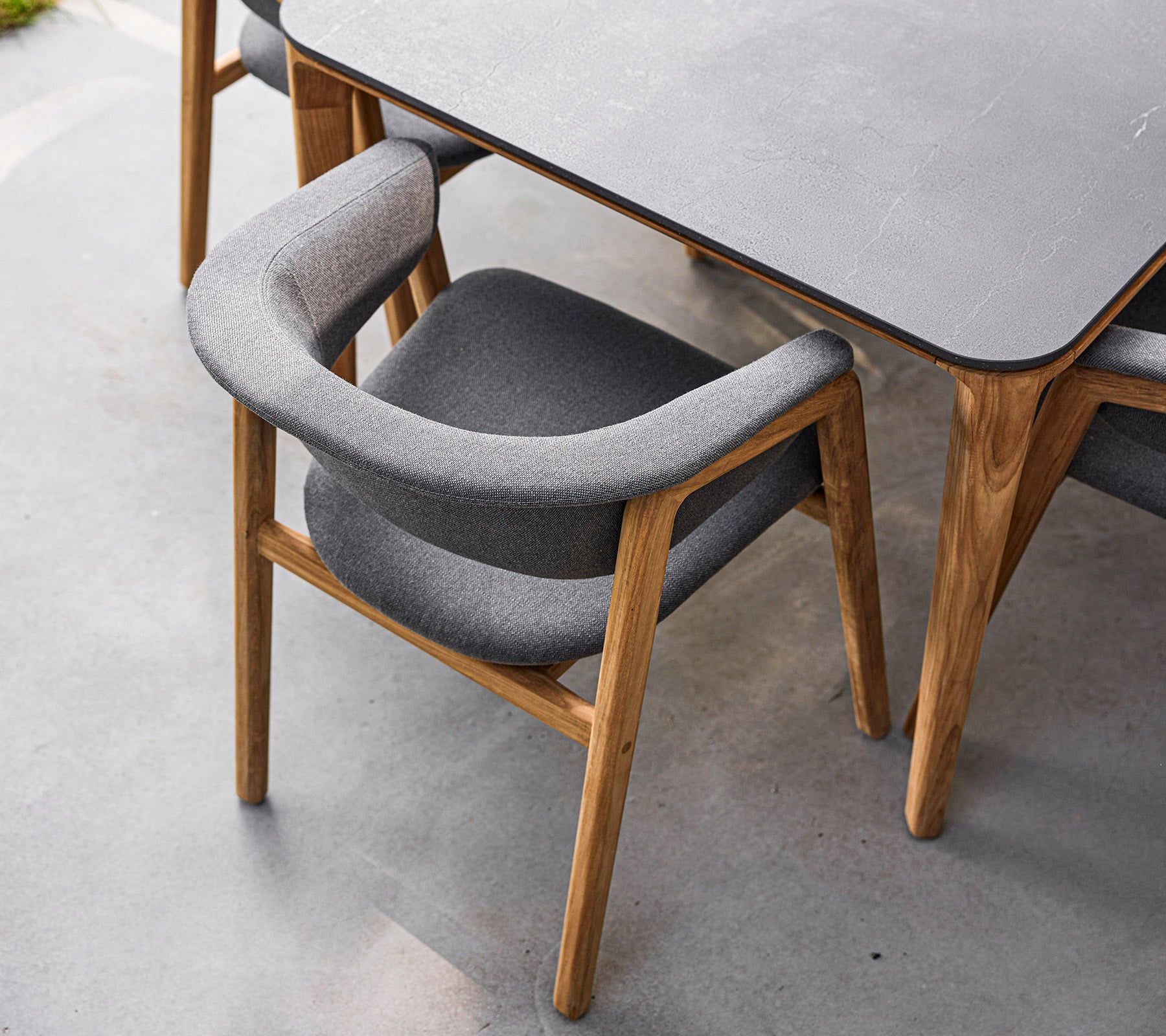 Chaise élégante avec un cadre en bois et un revêtement en gris doux, conçue pour le confort et l'élégance. Parfaite pour les salles à manger modernes.