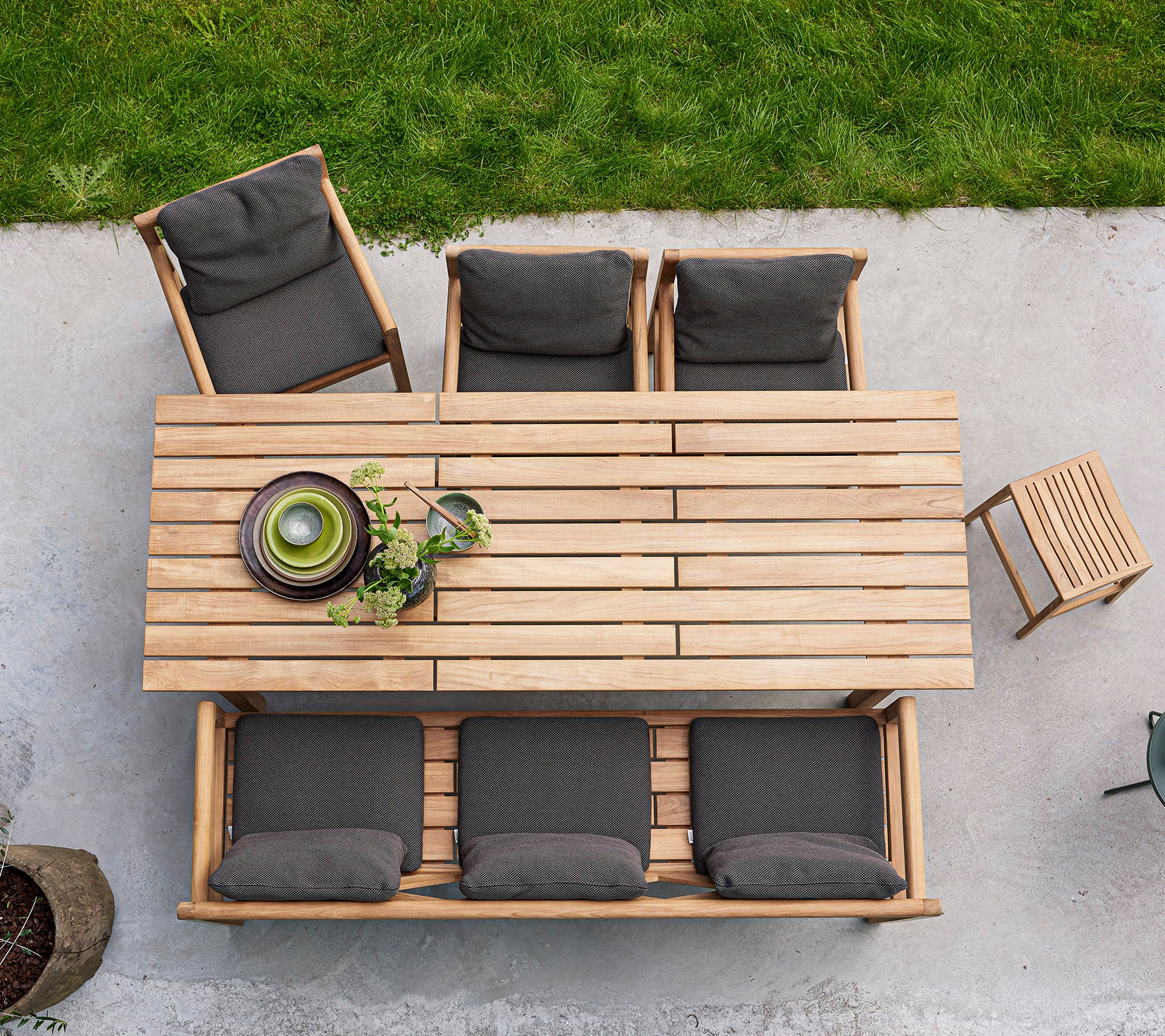 Une table à manger en bois avec quatre chaises rembourrées et un bol de verdure, disposée pour un rassemblement accueillant.