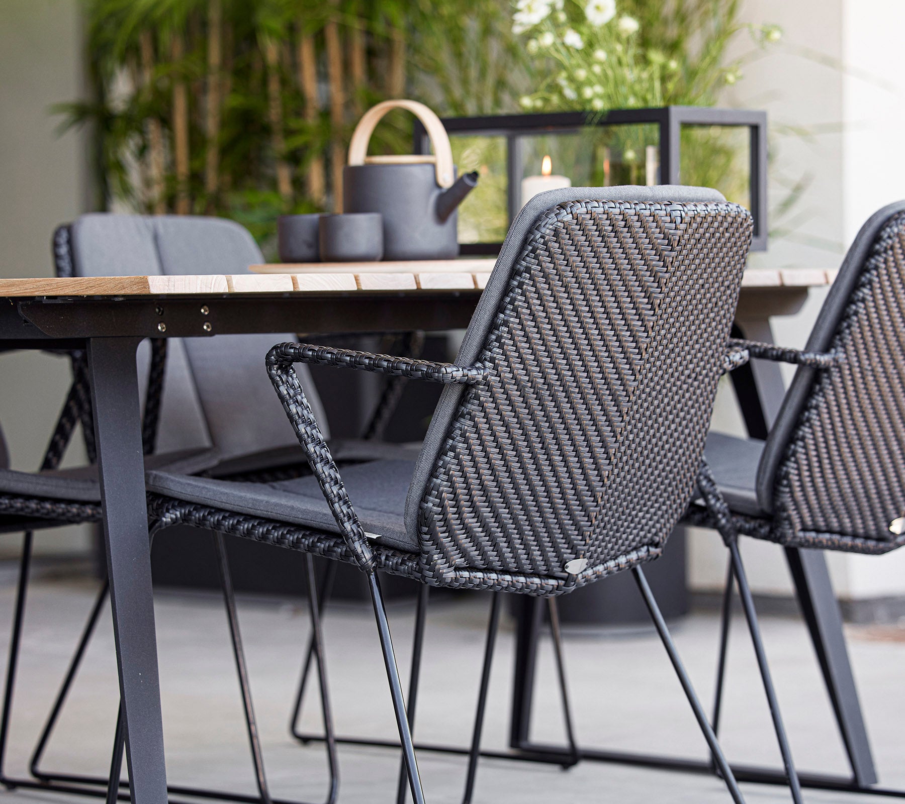 Sièges contemporains avec des chaises en osier gris autour d'une table en bois, complétés par des éléments décoratifs dans un agencement stylé.
