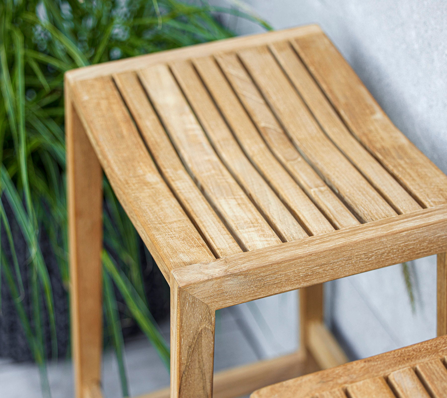 Une table d'appoint en bois au design de dessus en lattes, avec une finition claire qui complète la verdure environnante.
