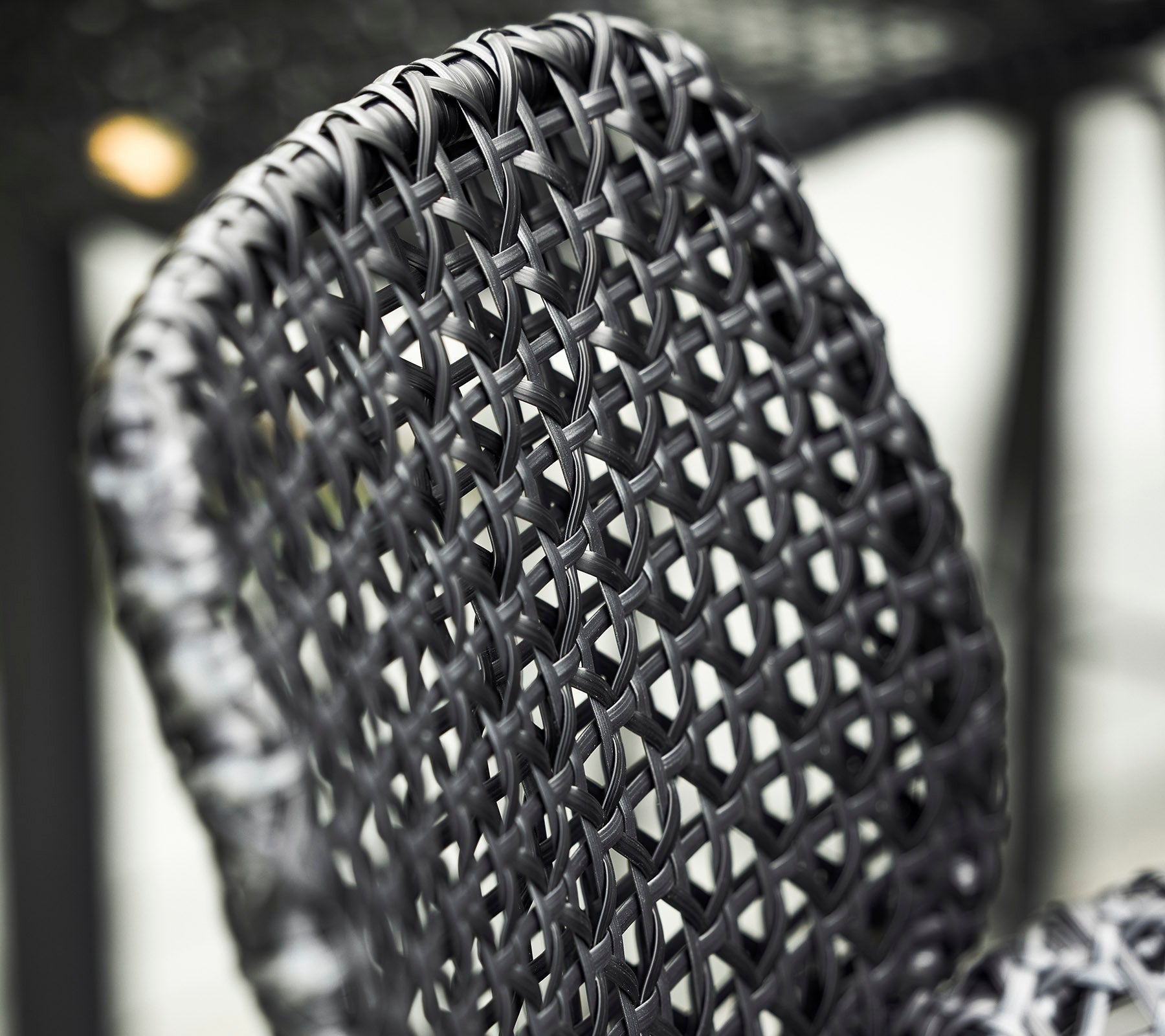 Gros plan d'un dossier de chaise en noir tissé, affichant des motifs et des textures complexes dans son design.