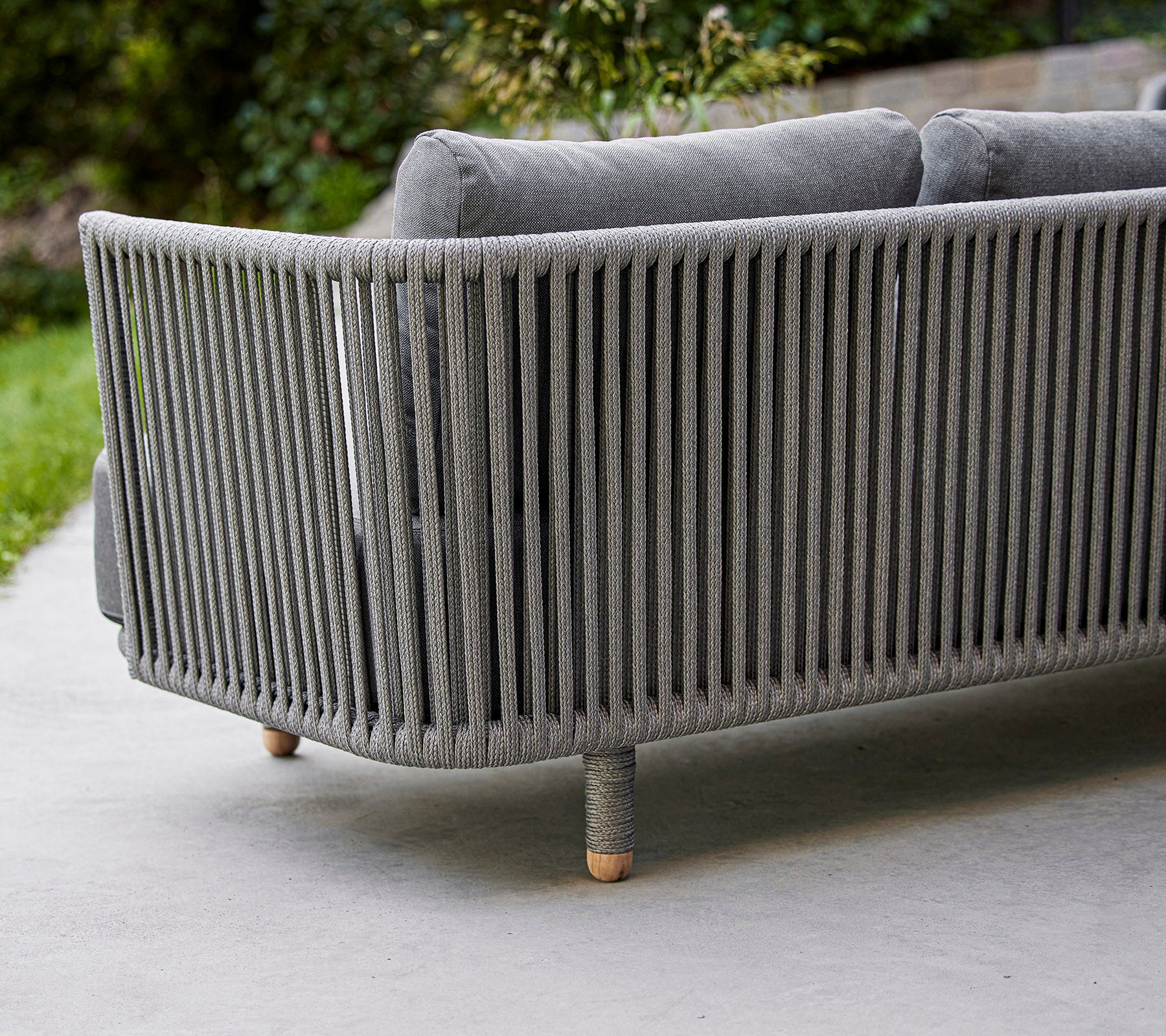 Canapé gris moderne et épuré avec design à lattes verticales et pieds en bois, idéal pour des espaces de vie ou extérieurs contemporains.