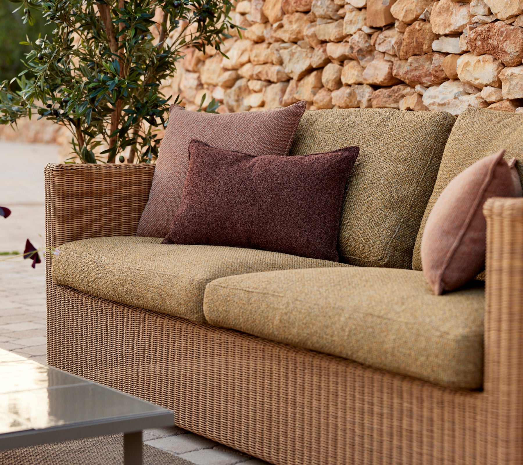 Canapé beige moderne avec des coussins violets et bruns dans un cadre de salon.