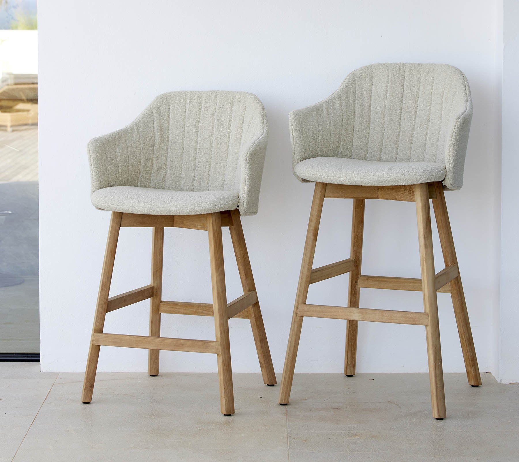Deux chaises élégantes de couleur claire avec des dossiers incurvés et des pieds en bois, présentant un design moderne et confortable.