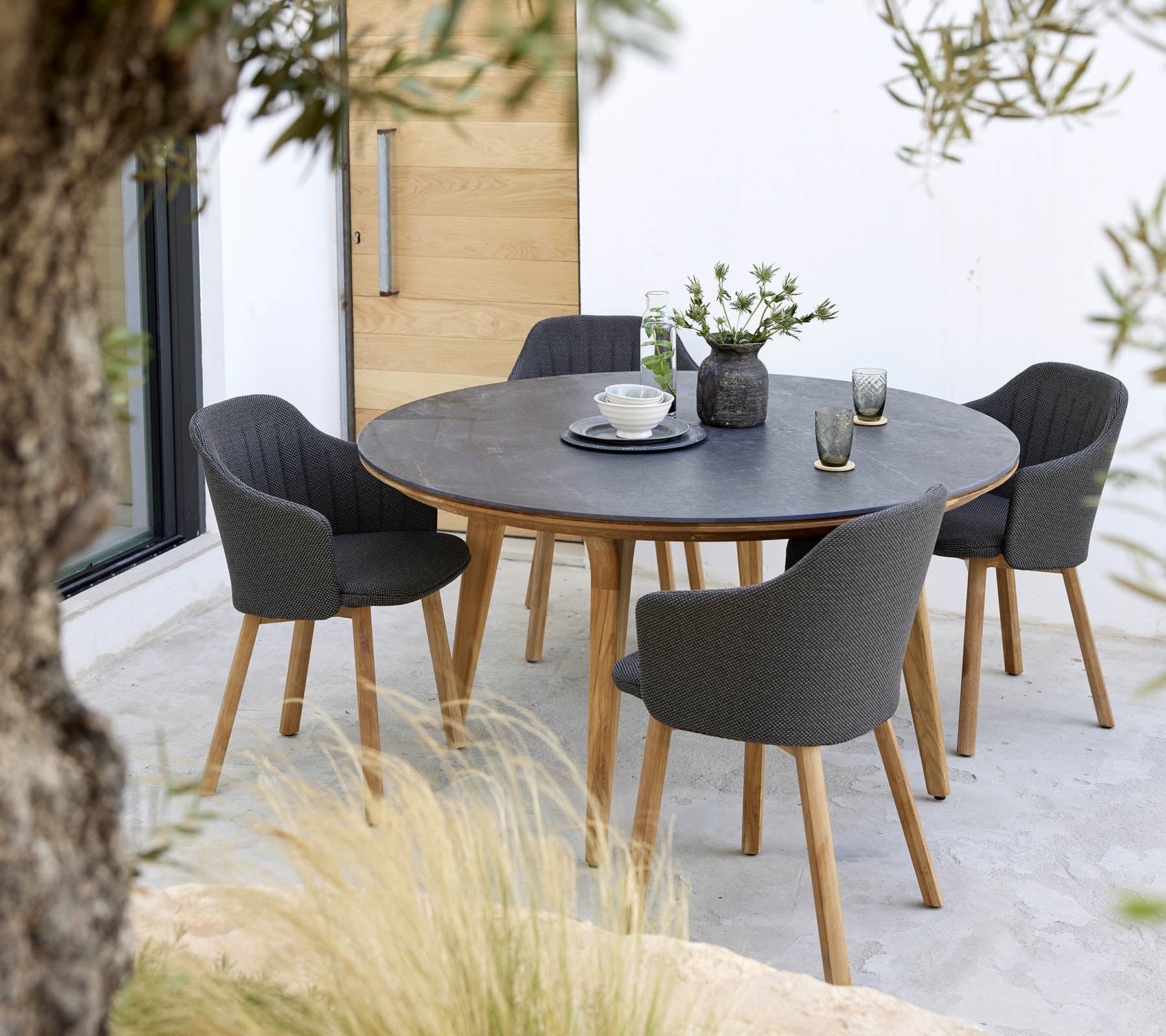 Une table ronde entourée de quatre chaises élégantes, avec un centre de table de fleurs et une simple décoration de table.