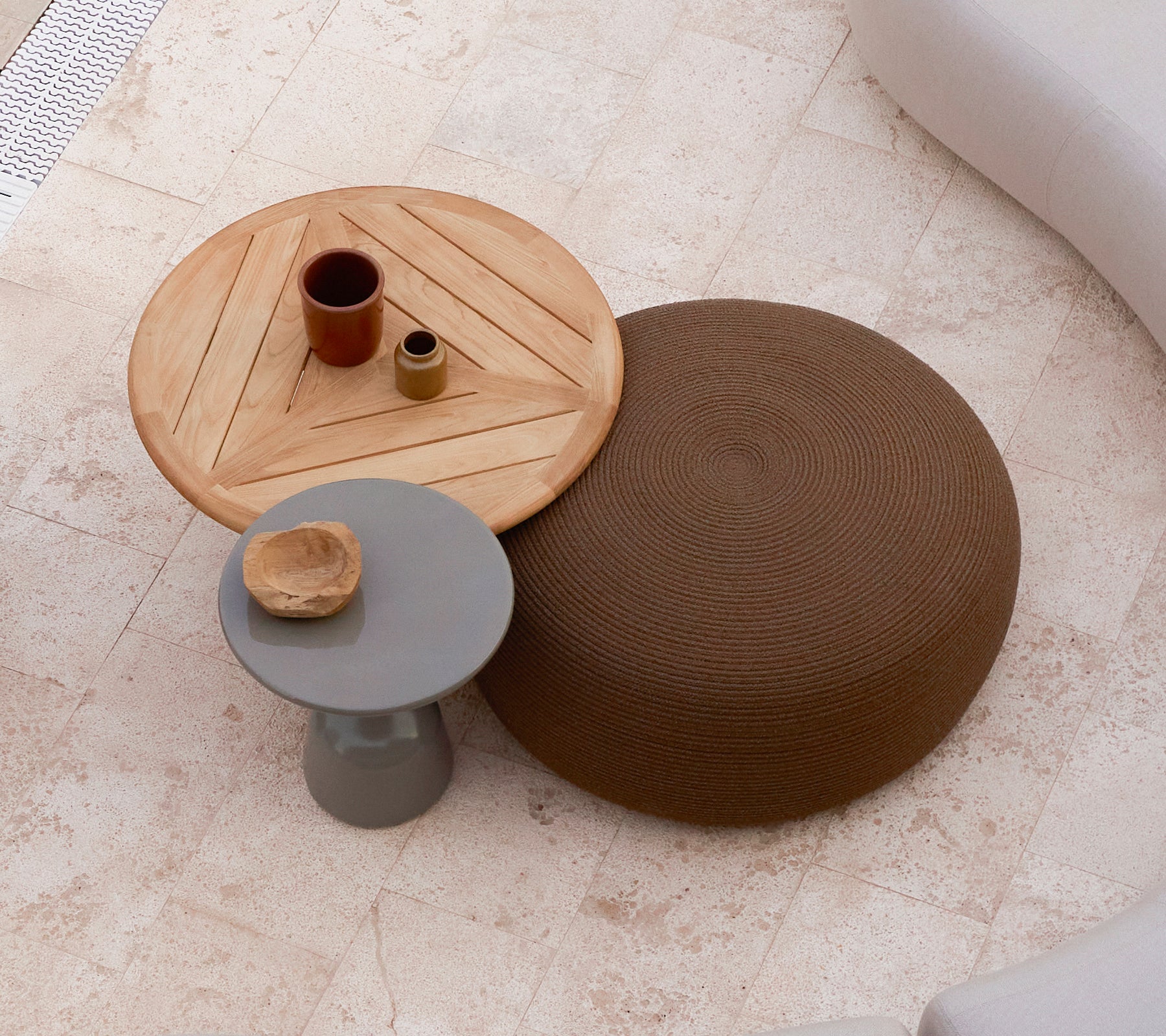 Un grand pouf rond en marron à côté d'une table basse en bois avec un design géométrique, comportant de petits objets décoratifs sur le dessus.
