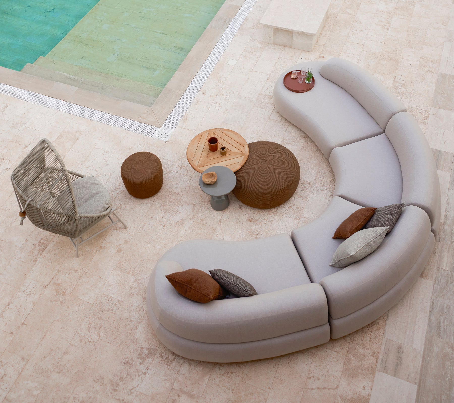 Des sièges de salon incurvés disposés avec de petits et grands repose-pieds ronds, aux côtés d'une chaise Hive et d'une table ronde dans un cadre élégant.