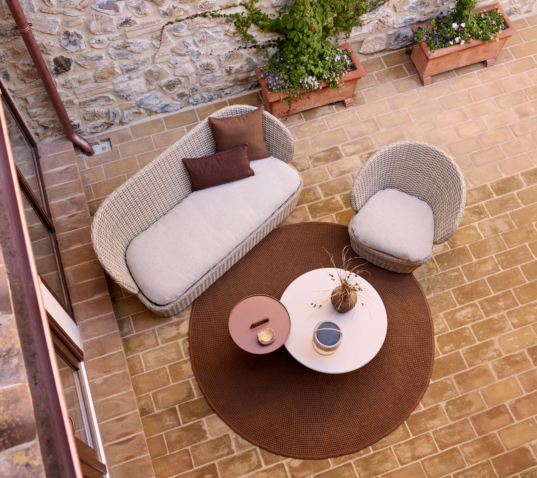 Espace lounge cozy avec un tapis tricoté, une table basse en verre et une lampe illusion, accentuée par des plantes en pot.