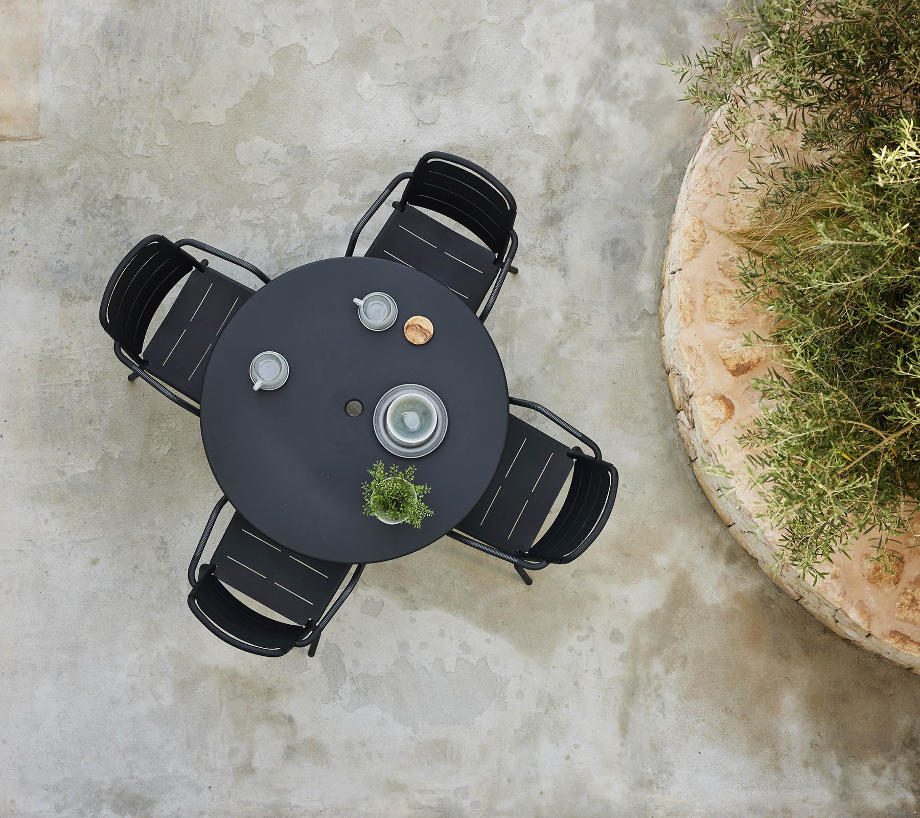 Une vue de dessus d'une table ronde entourée de chaises de Copenhague, avec des objets décoratifs et une petite plante.