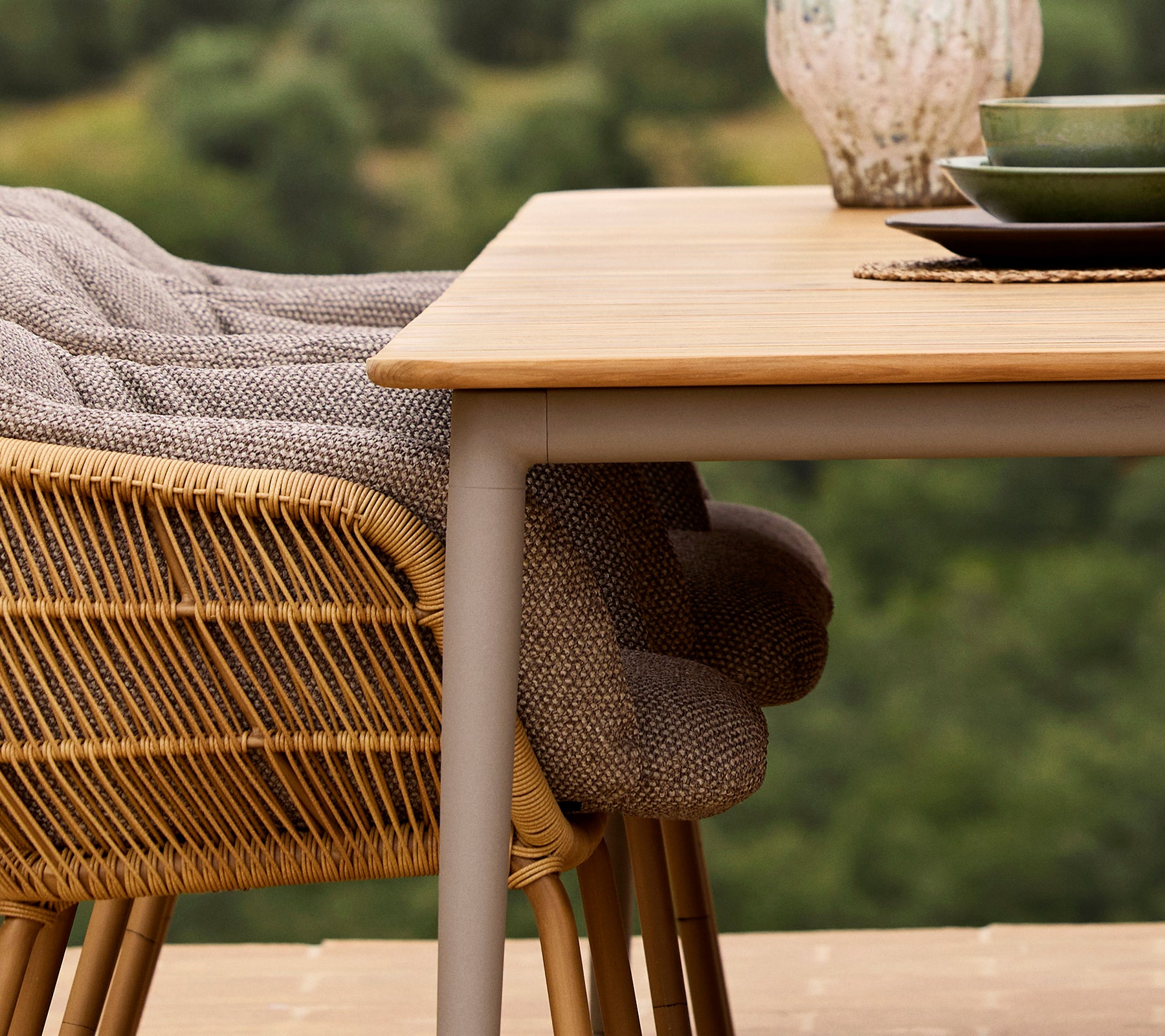 Un gros plan d'une table à manger Core avec une chaise Stay, présentant un tissu tissé et une assiette verte sur fond naturel.