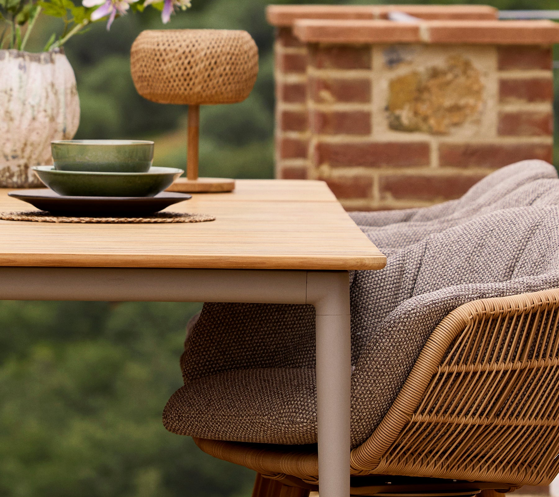 Une table à manger Core avec des assiettes vertes et un vase décoratif, accompagnée d'une chaise Stay avec un coussin confortable et d'une lampe Illusion Glow.