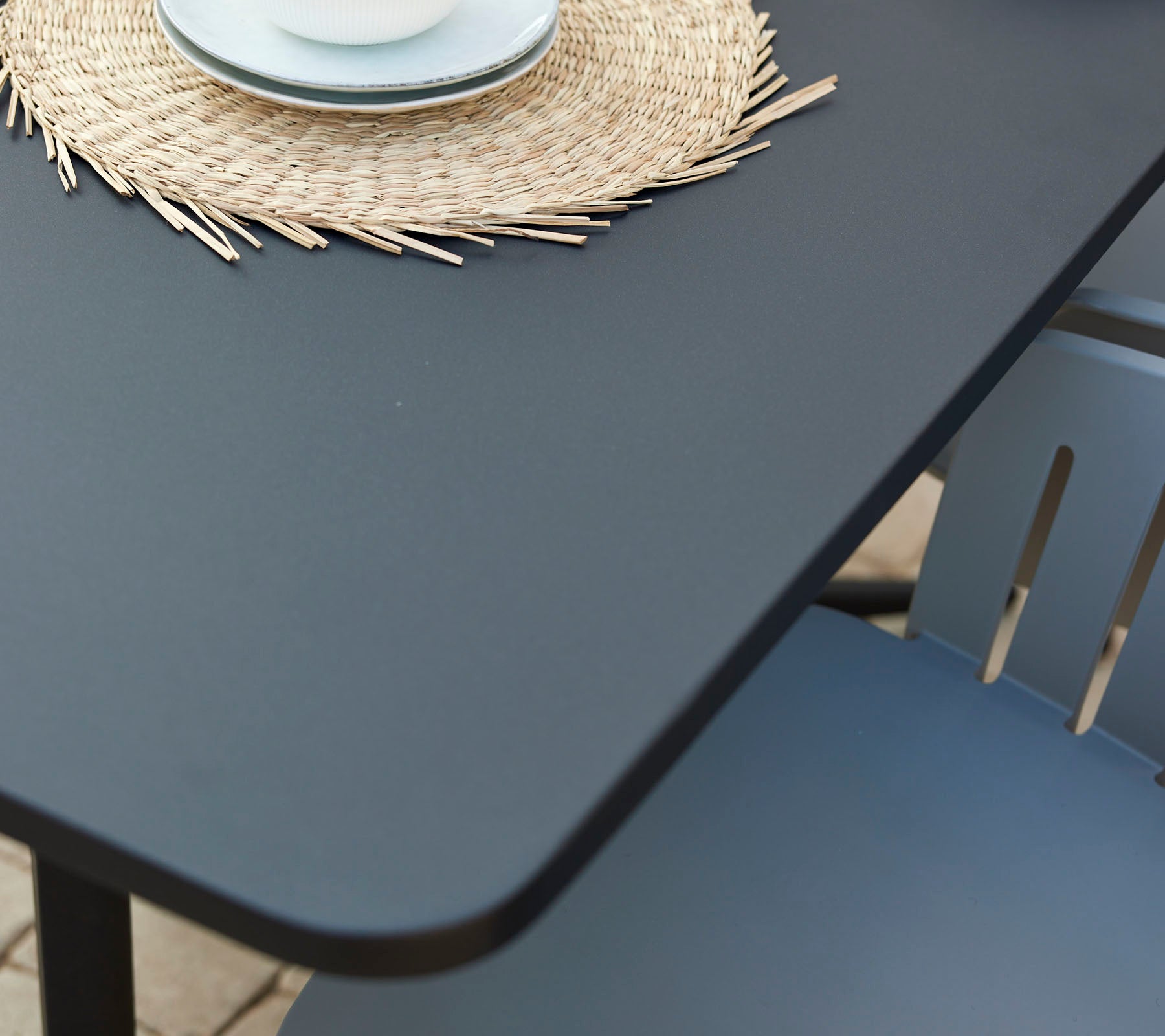Une table de café moderne avec une surface lisse, accompagnée d'un dessous de verre rond décoratif et d'une tasse sur une chaise confortable.