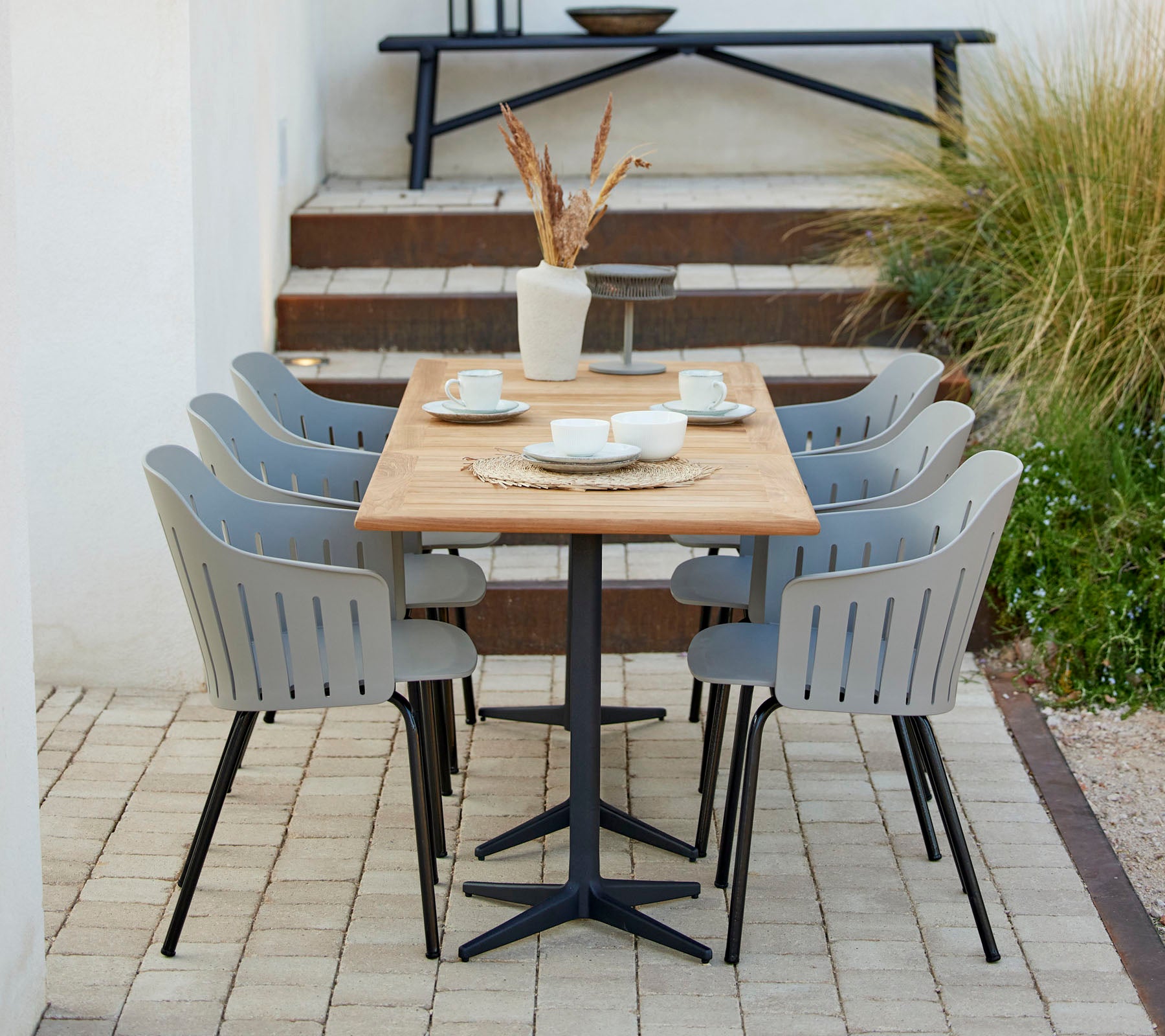 Un aménagement de salle à manger élégant avec une table en bois entourée de chaises grises, complété par des objets décoratifs et de la verdure.