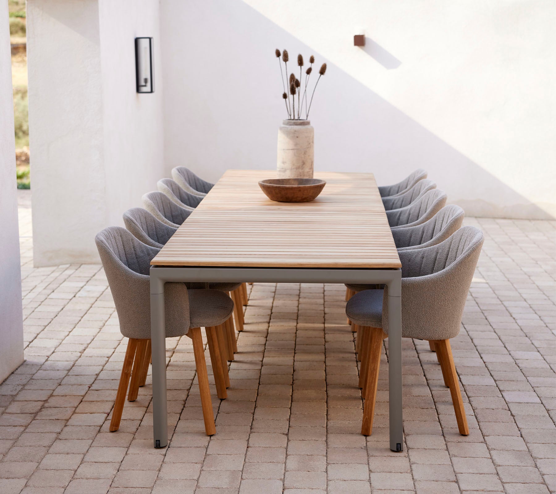 Une longue table avec des chaises modernes, décorée avec un vase et un bol, créant un espace accueillant pour les rassemblements.