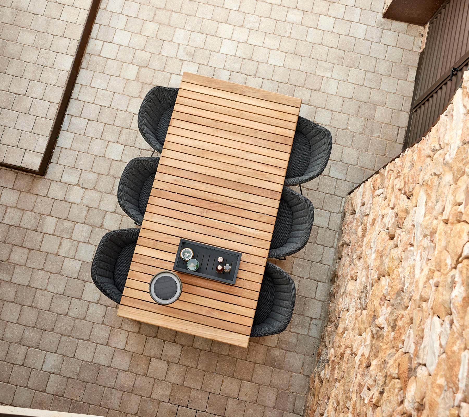 Une table en bois moderne avec quatre chaises noires élégantes, présentant un arrangement central de boissons et de collations.
