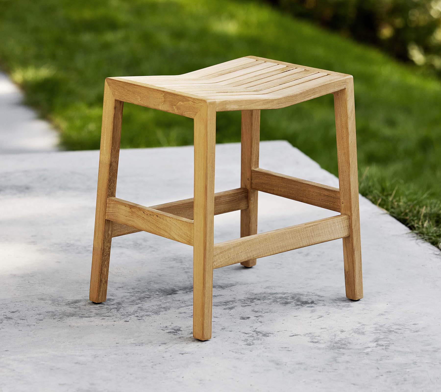 Un tabouret en bois rabattable avec un siège à lattes et des pieds robustes, conçu pour un usage polyvalent comme siège ou décoratif.