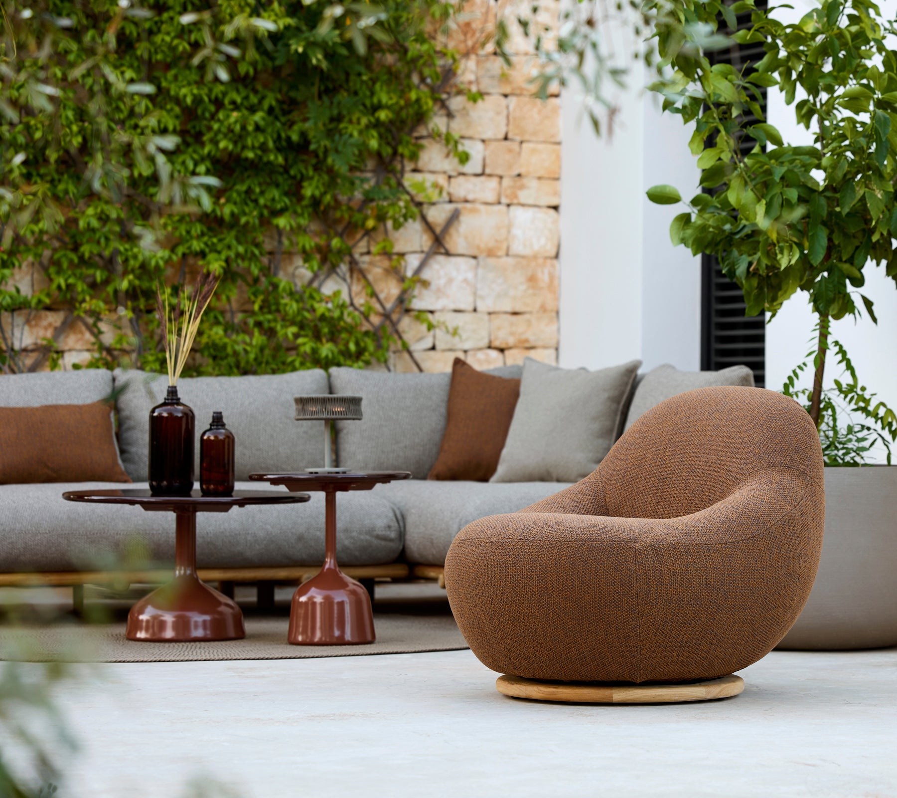 Espace lounge moderne avec un fauteuil marron, un canapé gris et une table d'appoint marron.